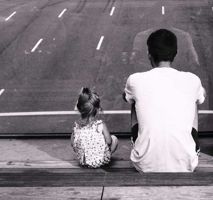 Un padre está sentado con su hija pequeña, compartiendo un momento especial. | Foto: Unsplash