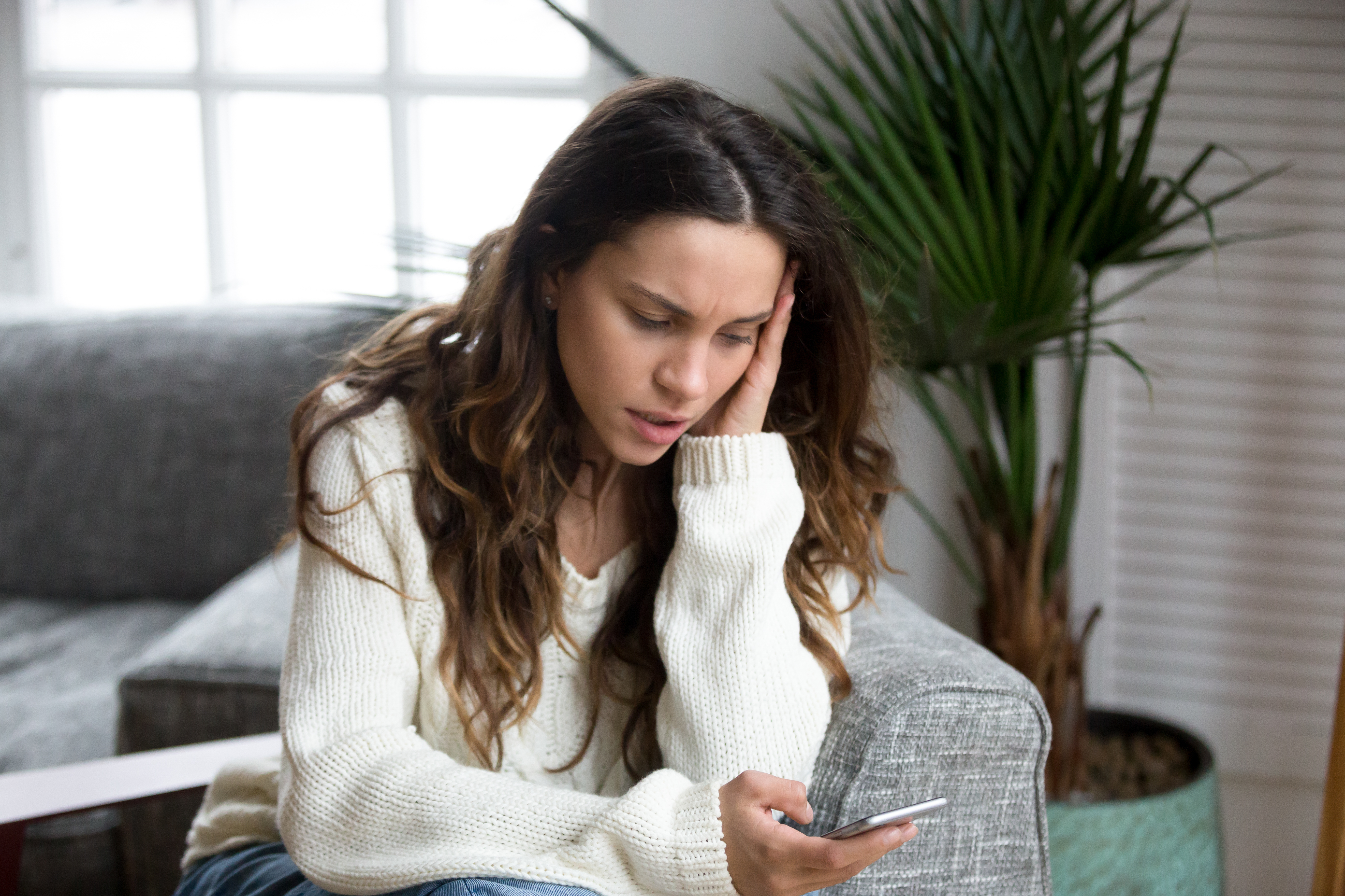 Woman feeling upset while reading messages on a smartphone | Source: Shutterstock