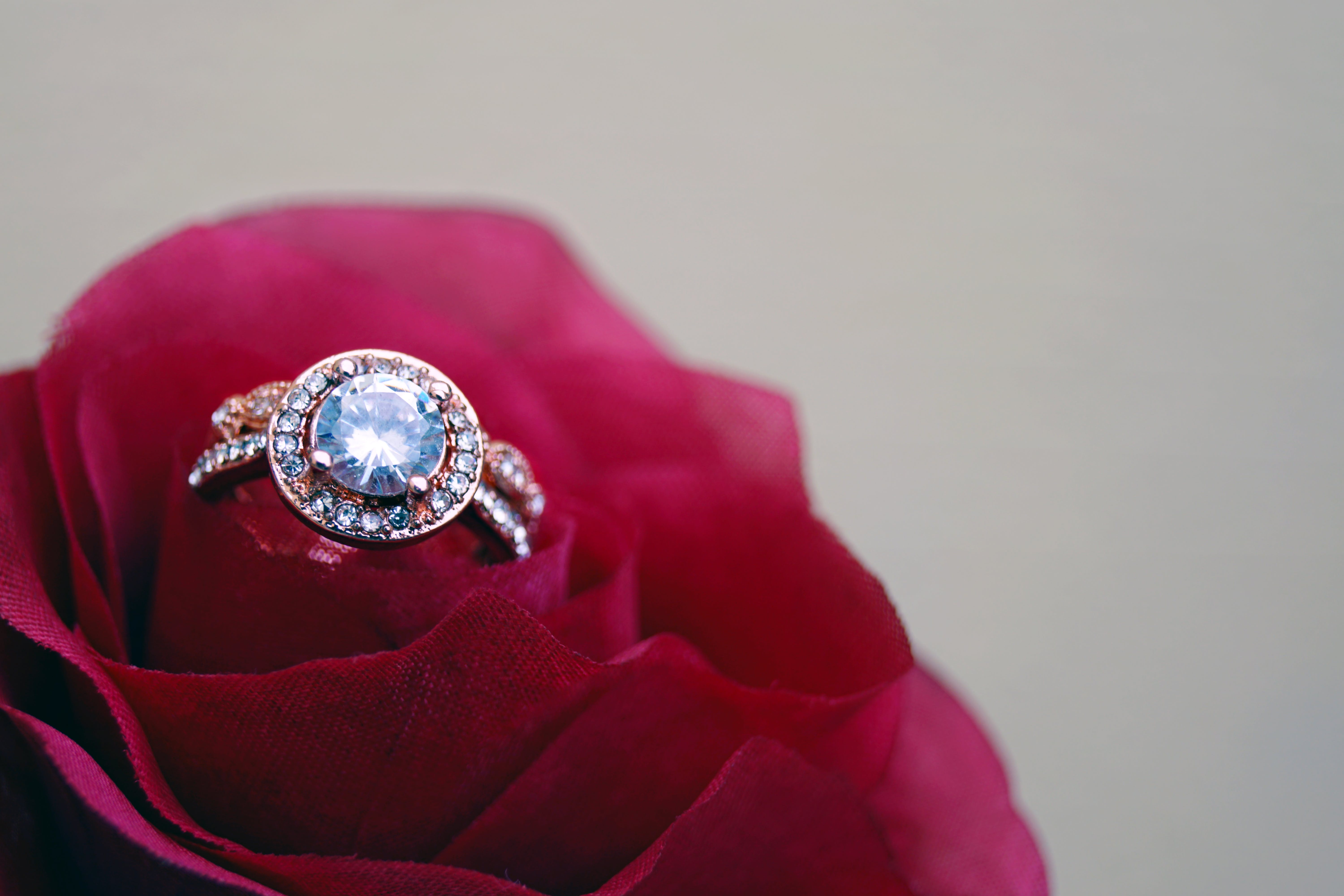 A close up of clear jeweled gold-colored cluster ring on a rose | Source: Pexels
