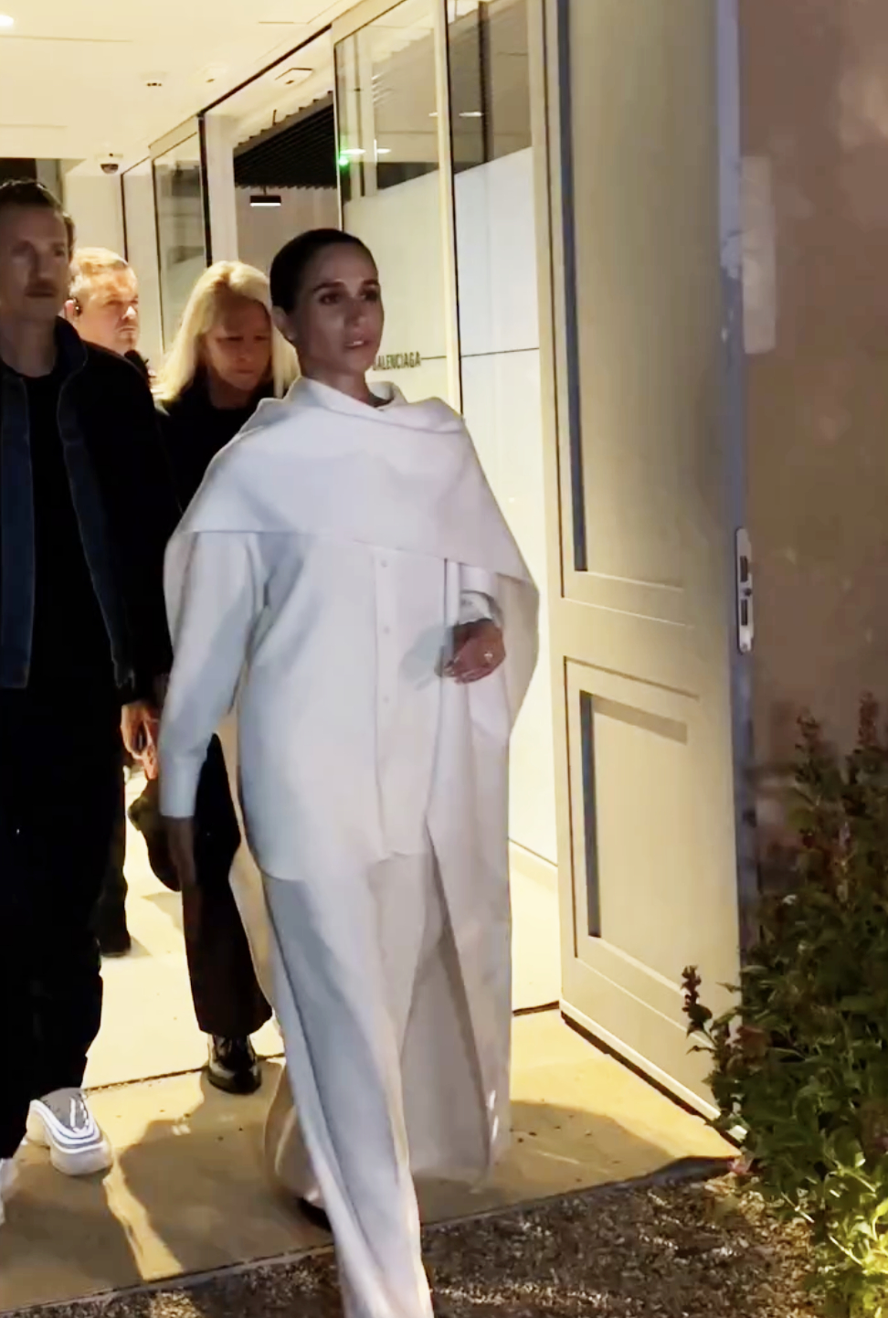 Meghan Markle, the Duchess of Sussex, walks with confidence and elegance at Paris Fashion Week, dressed in a sophisticated all-white ensemble that highlights her refined, minimalist style.