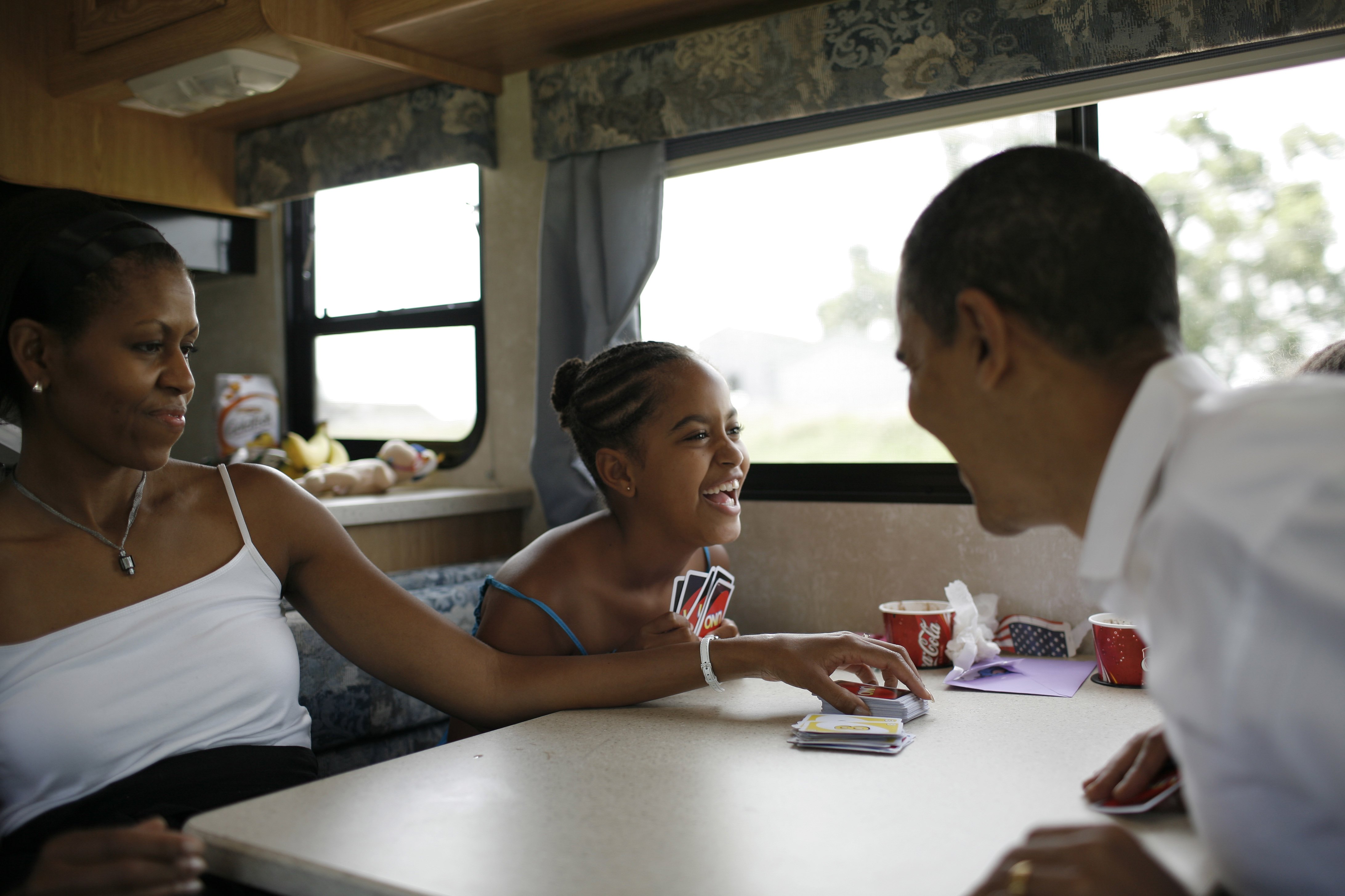 Michelle, Malia, Sasha (not pictured) and Barack Obama playing cards in their RV  while on a campaign swing between Oskaloosa and Pella, Iowa on July 4, 2007. | Source: Getty Images