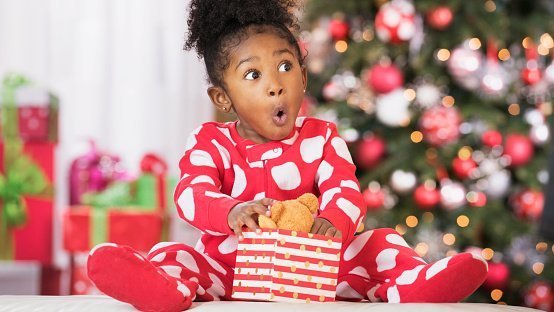 Surprised girl holding a wrapped gift on Christmas | Photo: Getty Images