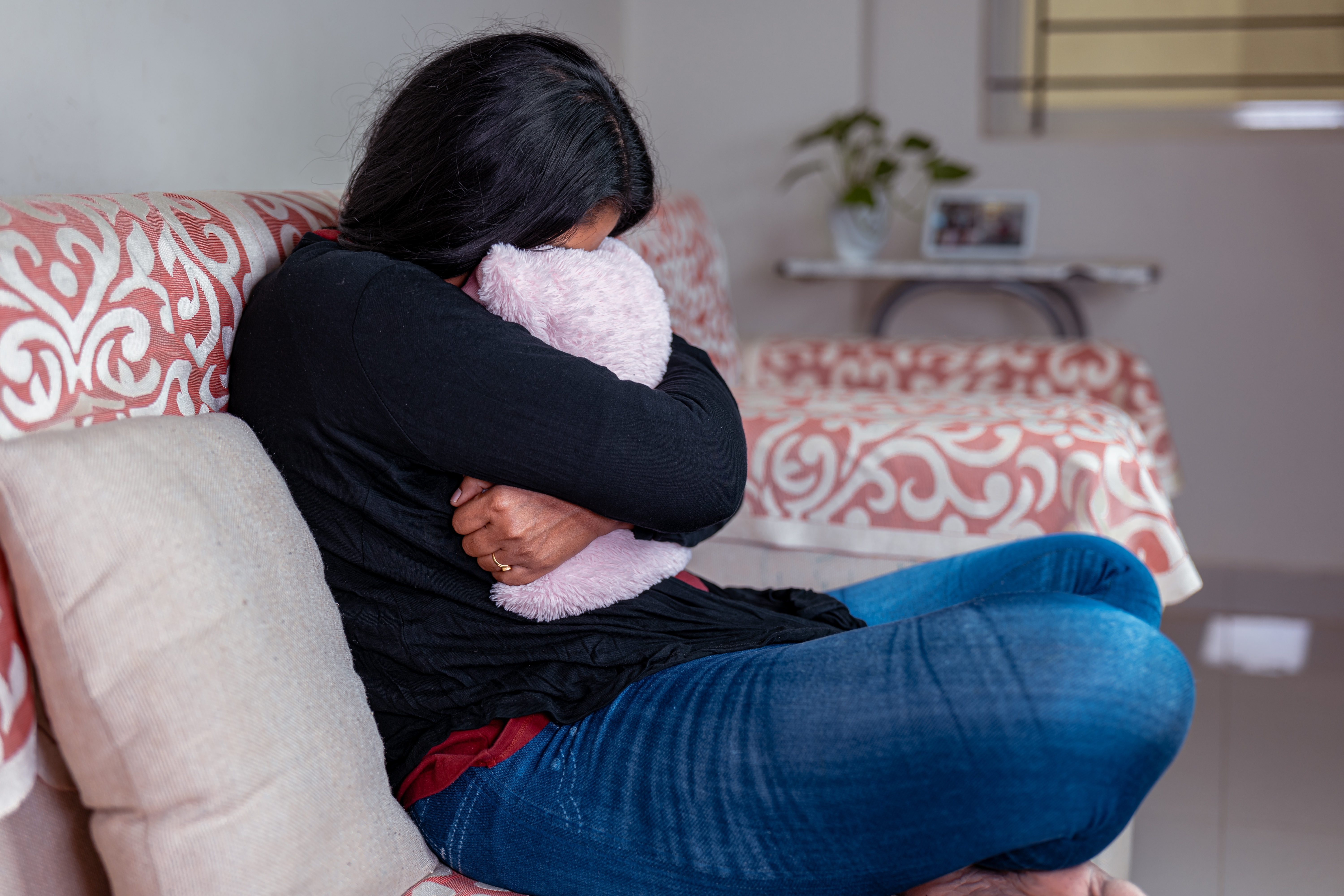 Woman hugging a pillow as she cries | Source: Shutterstock