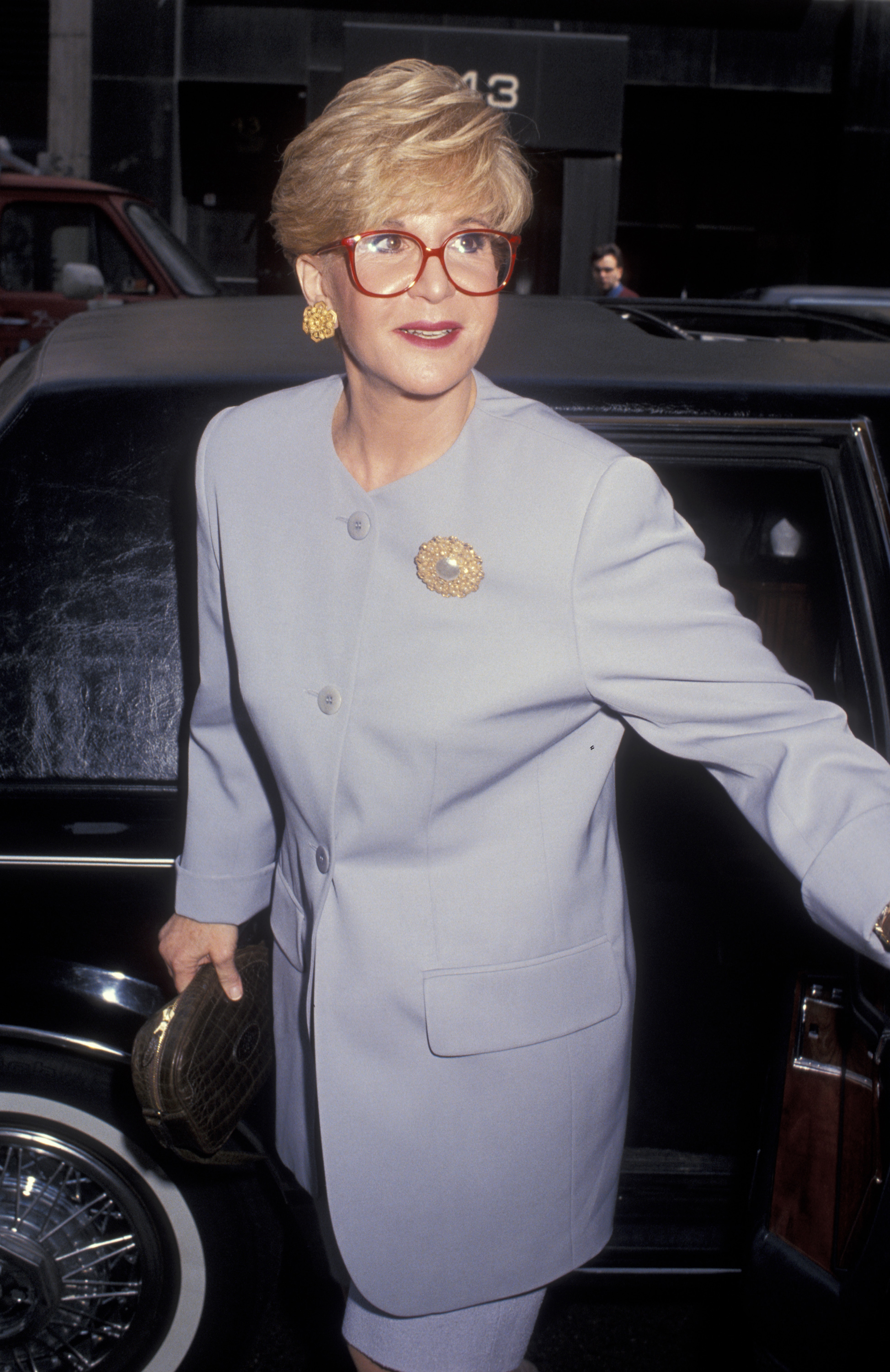 Sally Jessy Raphael steps out of a car ahead of a taping of "The Sally Jessy Raphael Show" at Unitel Studios in New York City on April 12, 1993. Dressed in a pale lavender suit with gold accessories and her trademark red glasses, the talk show host exudes poise and professionalism.