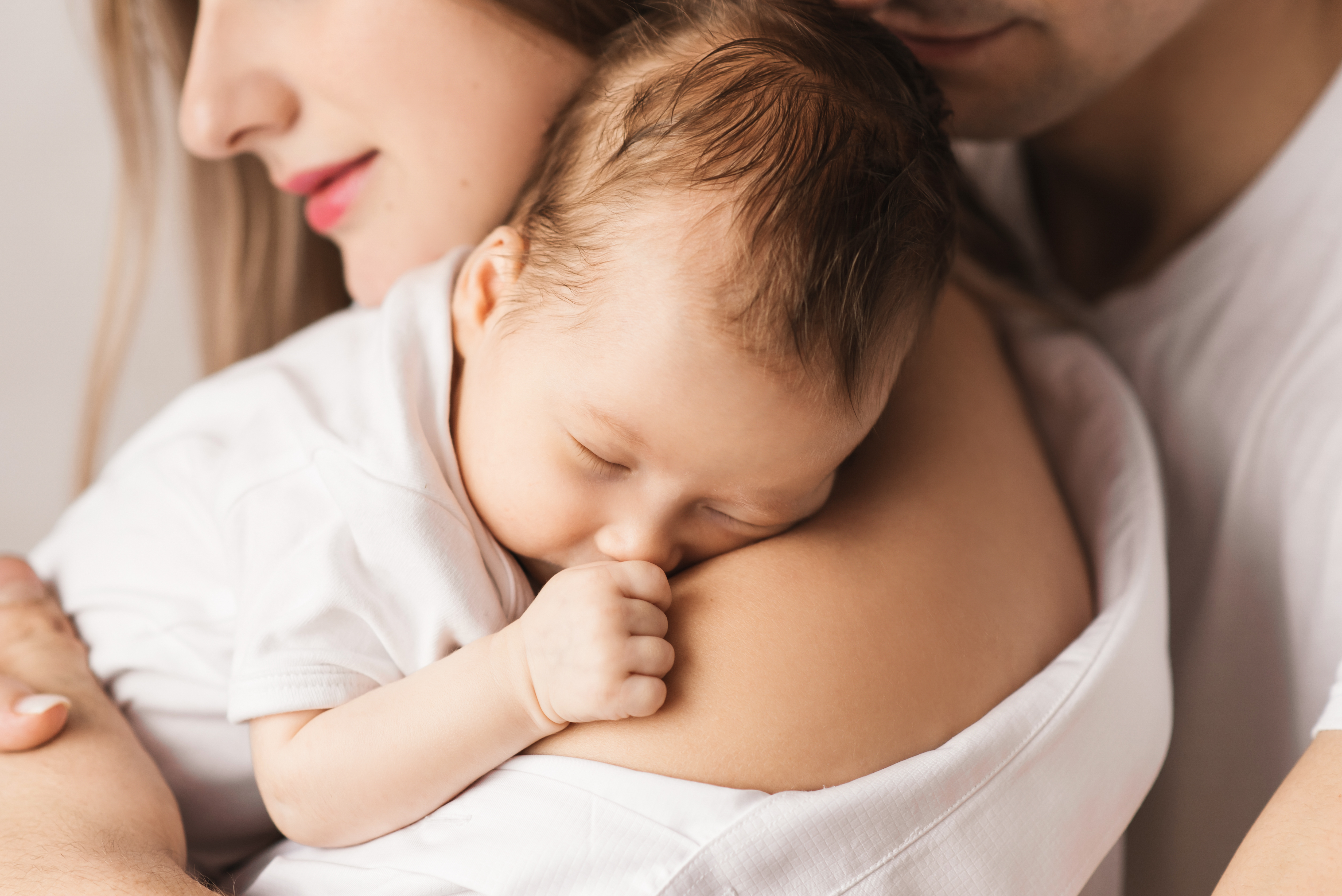 A mother holds her baby as her husband stands behind them | Source: Shutterstock