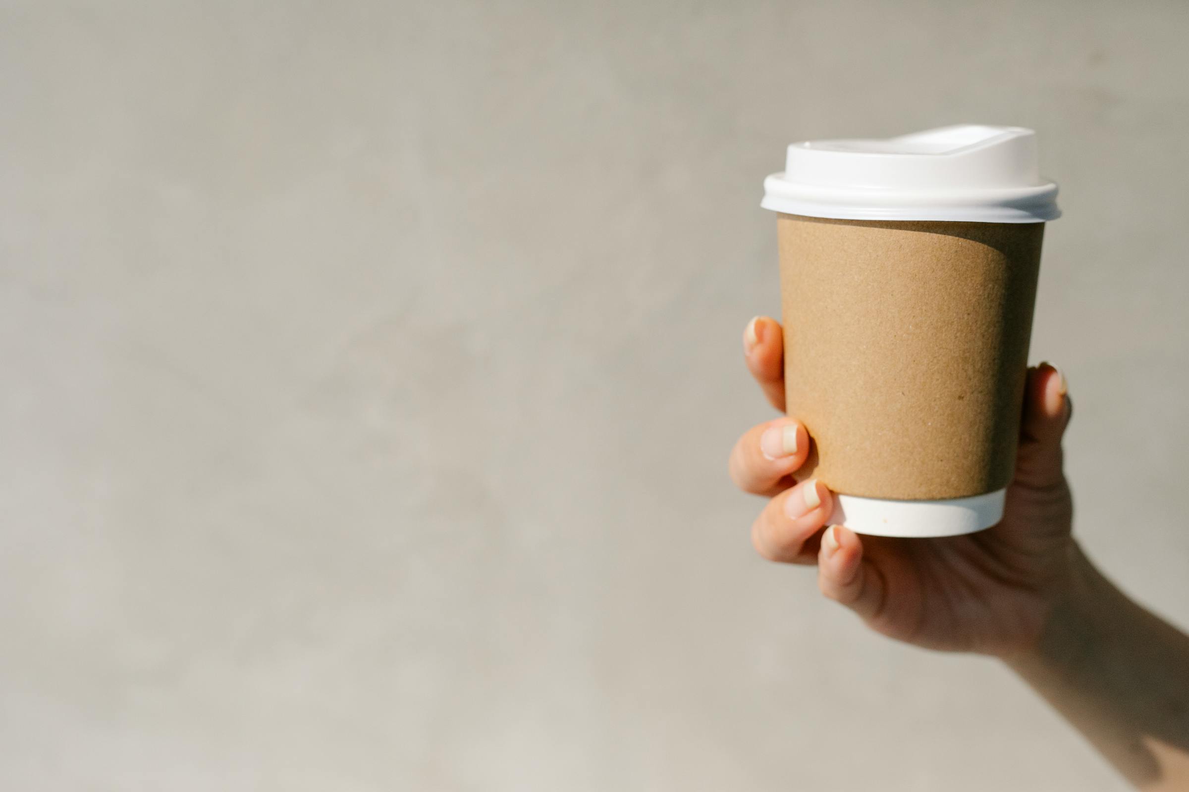 Holding a to-go coffee cup | Source: Pexels