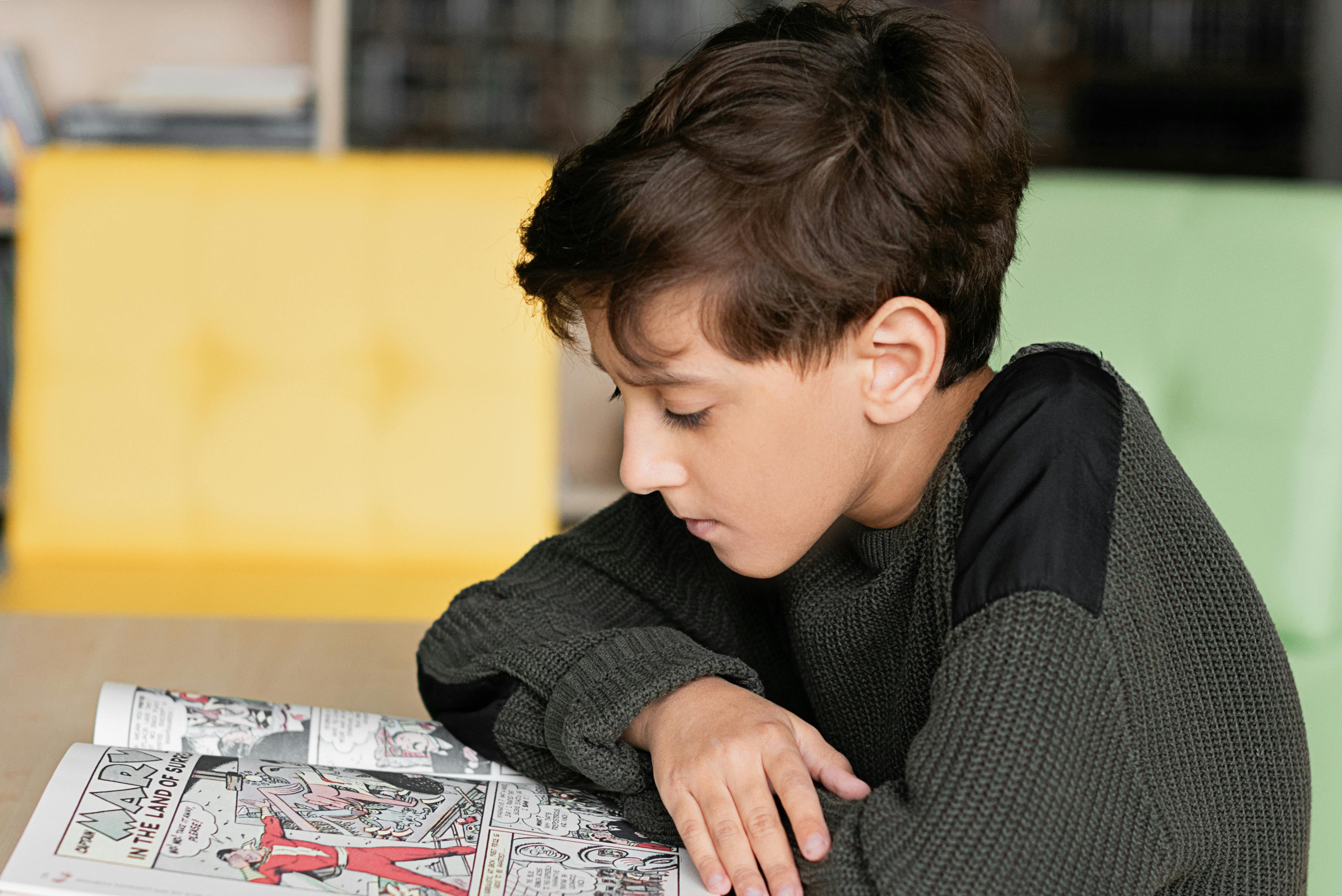 A young boy reading a comic book | Source: Pexels