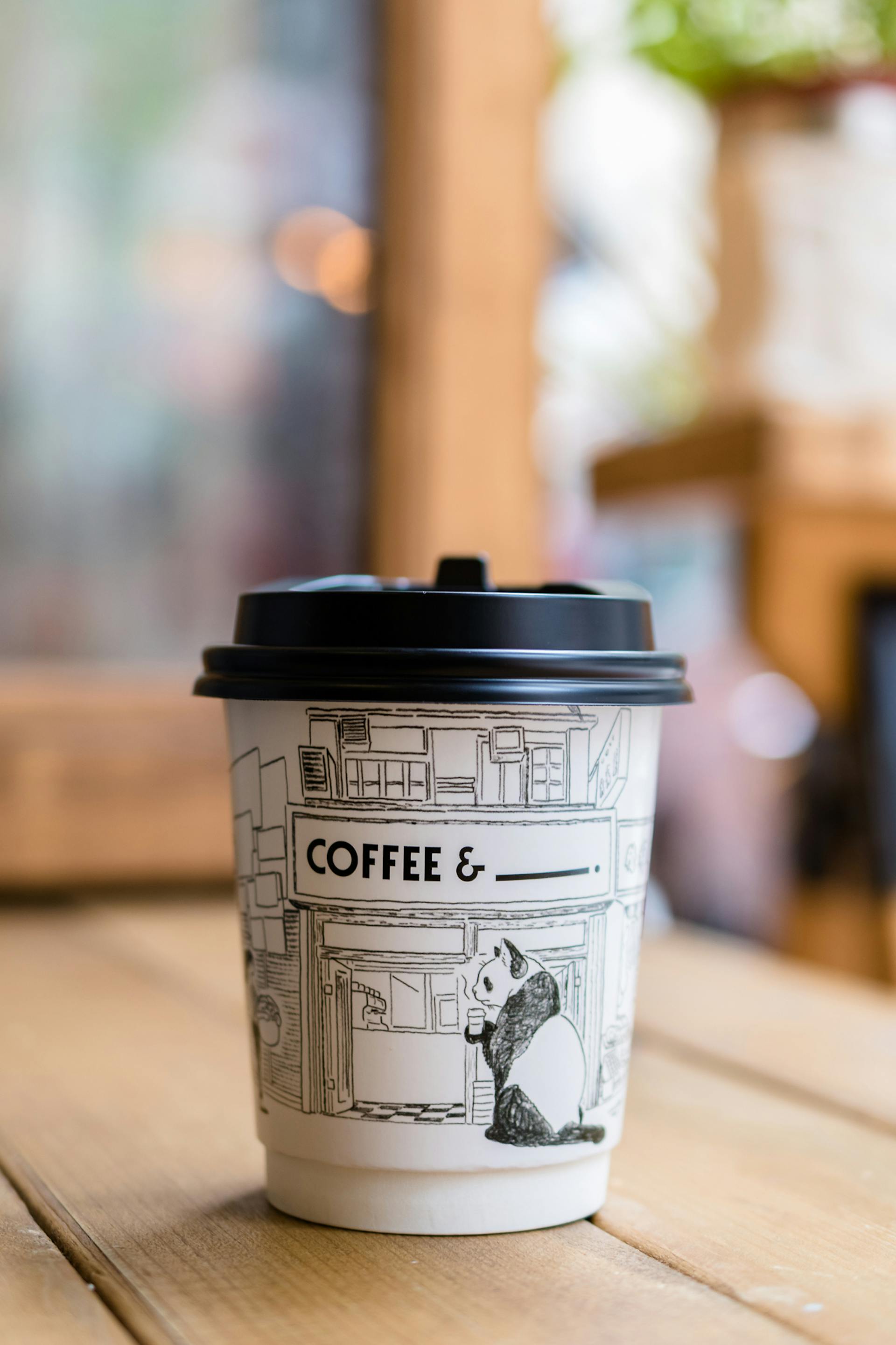 Coffee in a panda-printed paper cup lying on a table | Source: Pexels