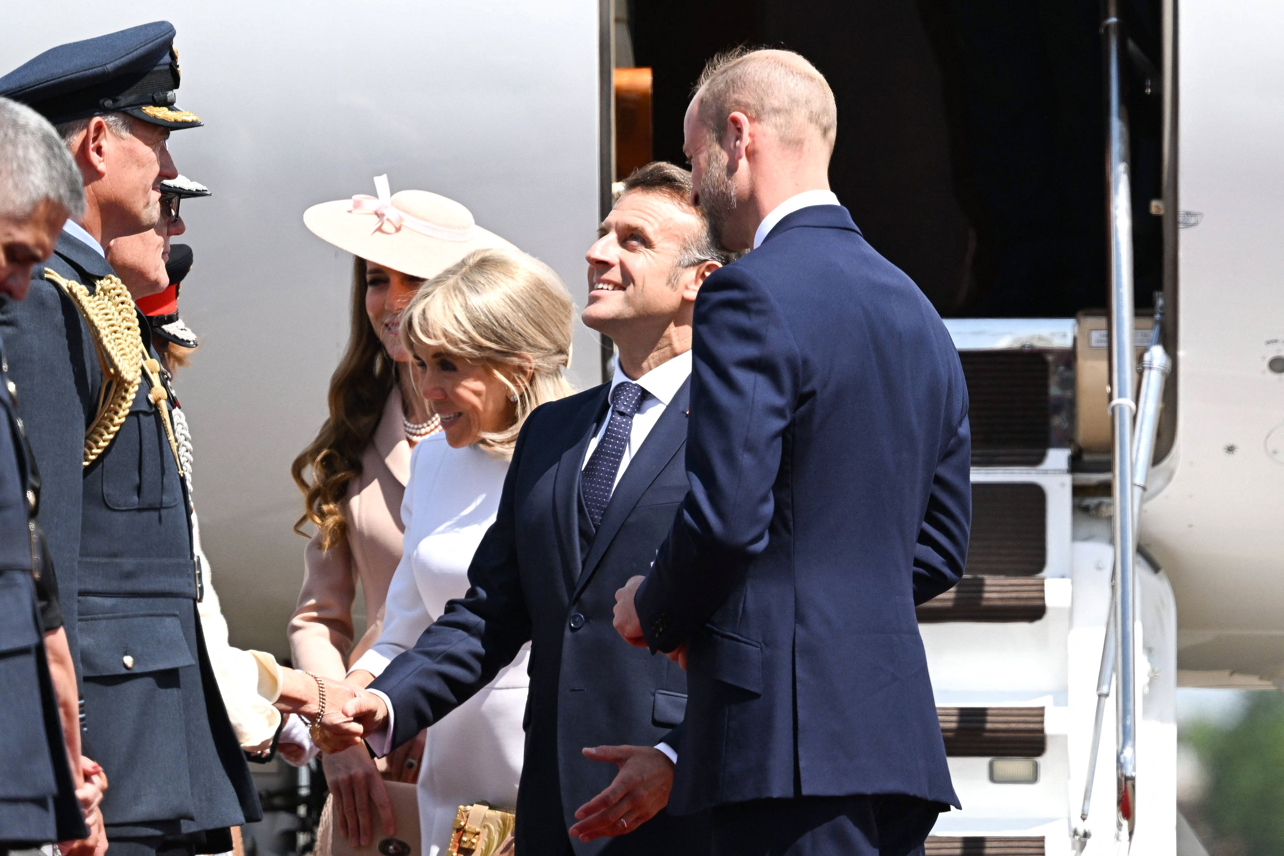 French President Emmanuel Macron greets British service members in uniform upon his arrival at RAF Northolt, as Prince William, First Lady Brigitte Macron, and Princess Catherine look on.