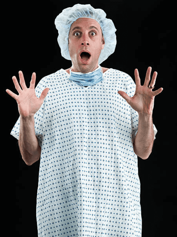 Scared patient in a hospital gown holds his hands up | Source: Getty Images