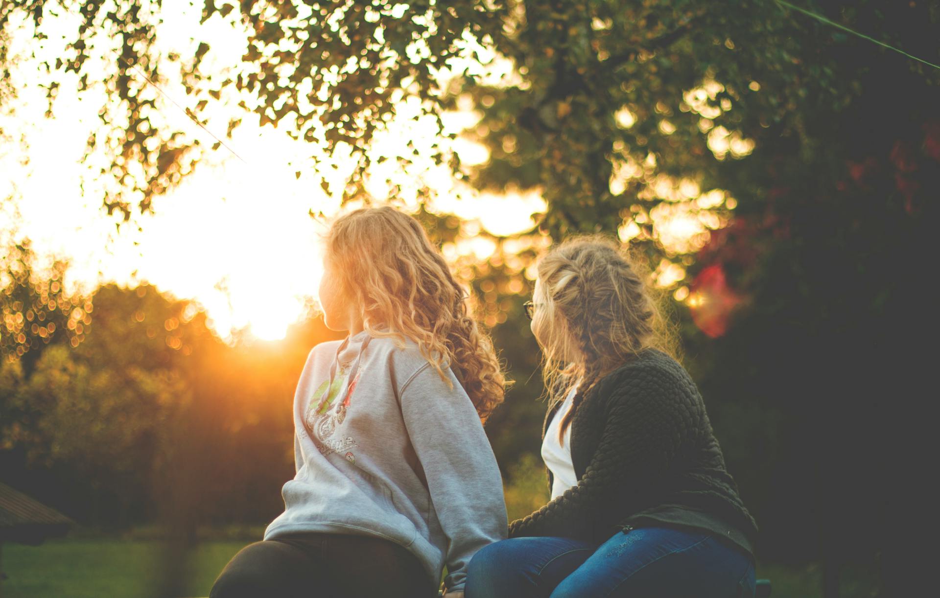 Two women sitting near a tree during sunset | Source: Pexels