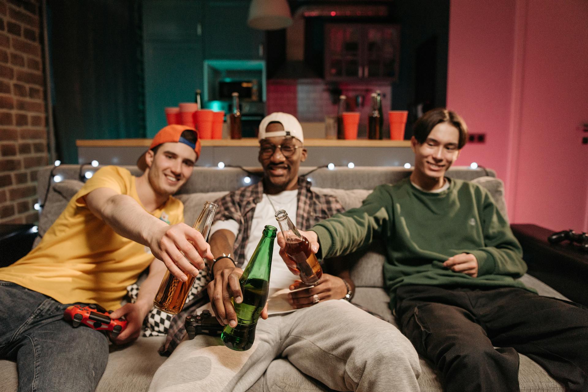 Men toasting with their beer bottles during a game night at home | Source: Pexels