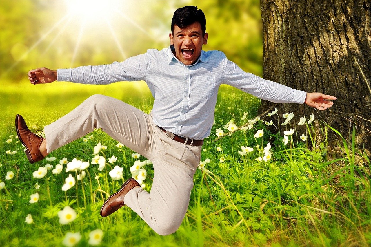 A formally dressed man jumping in the air for joy with greenery in the background | Photo: Pixabay/Alexas_Fotos 