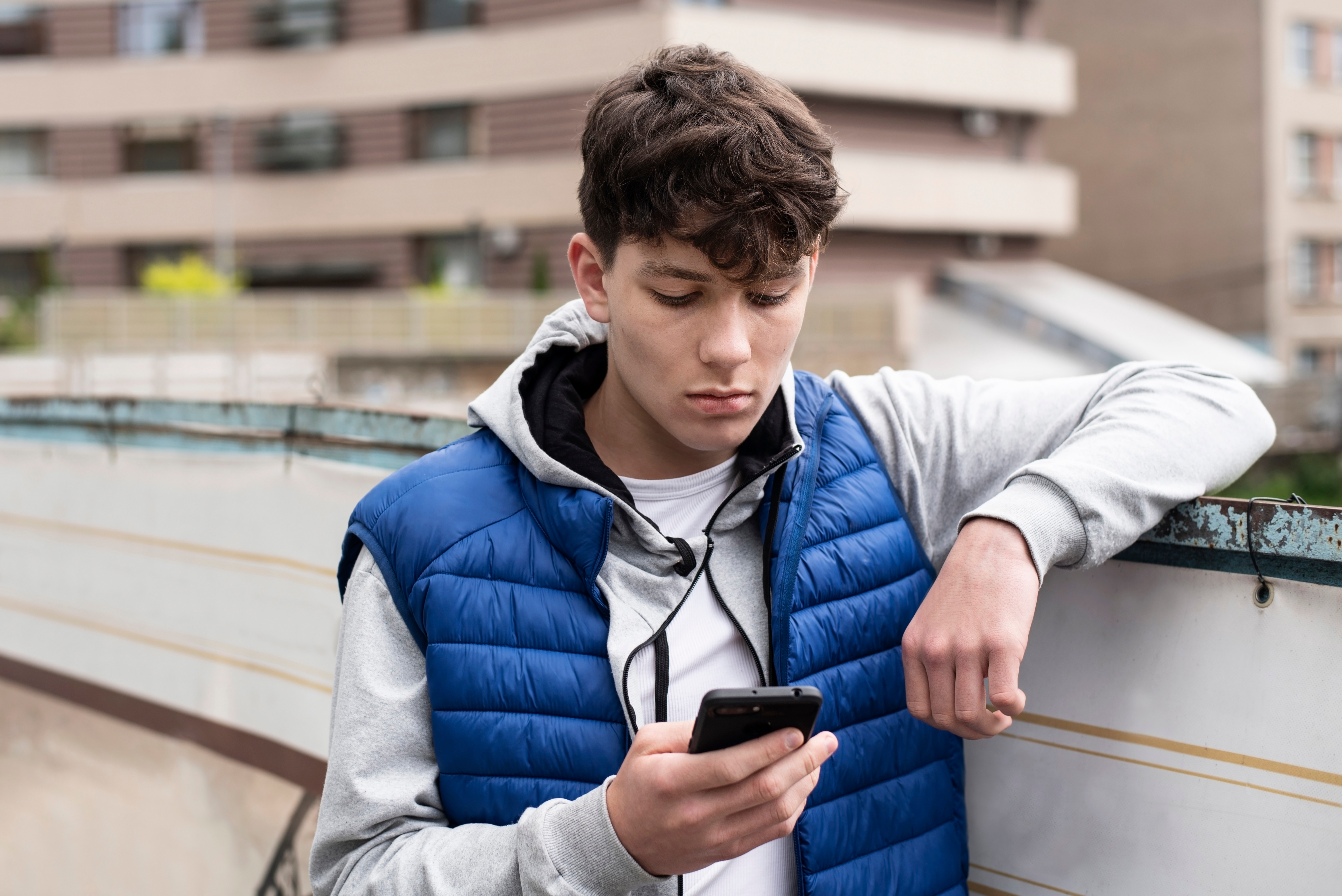 A teen boy looking into his phone | Source: Shutterstock