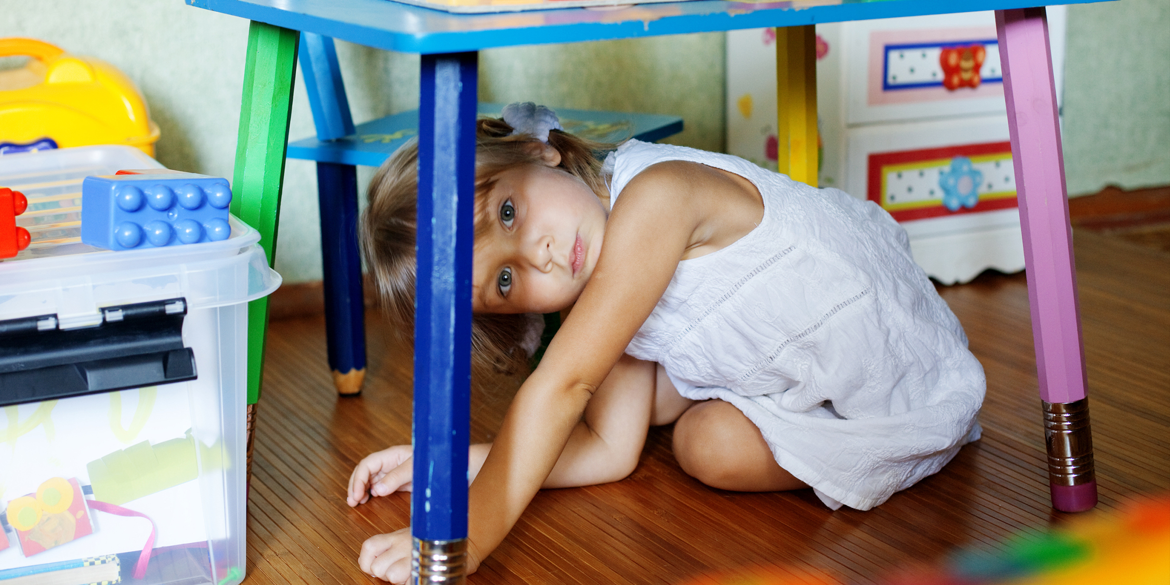 A child hiding under a table | Source: Shutterstock