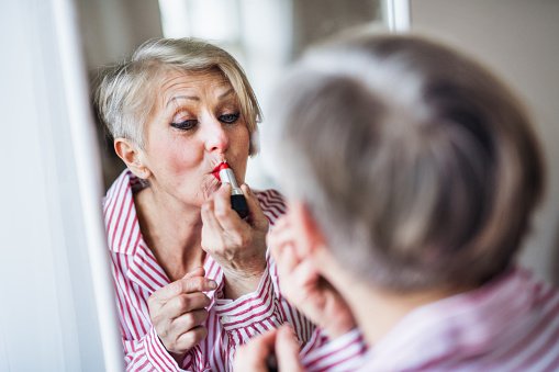 Une femme âgée en train de se maquiller. | Photo : Getty Images