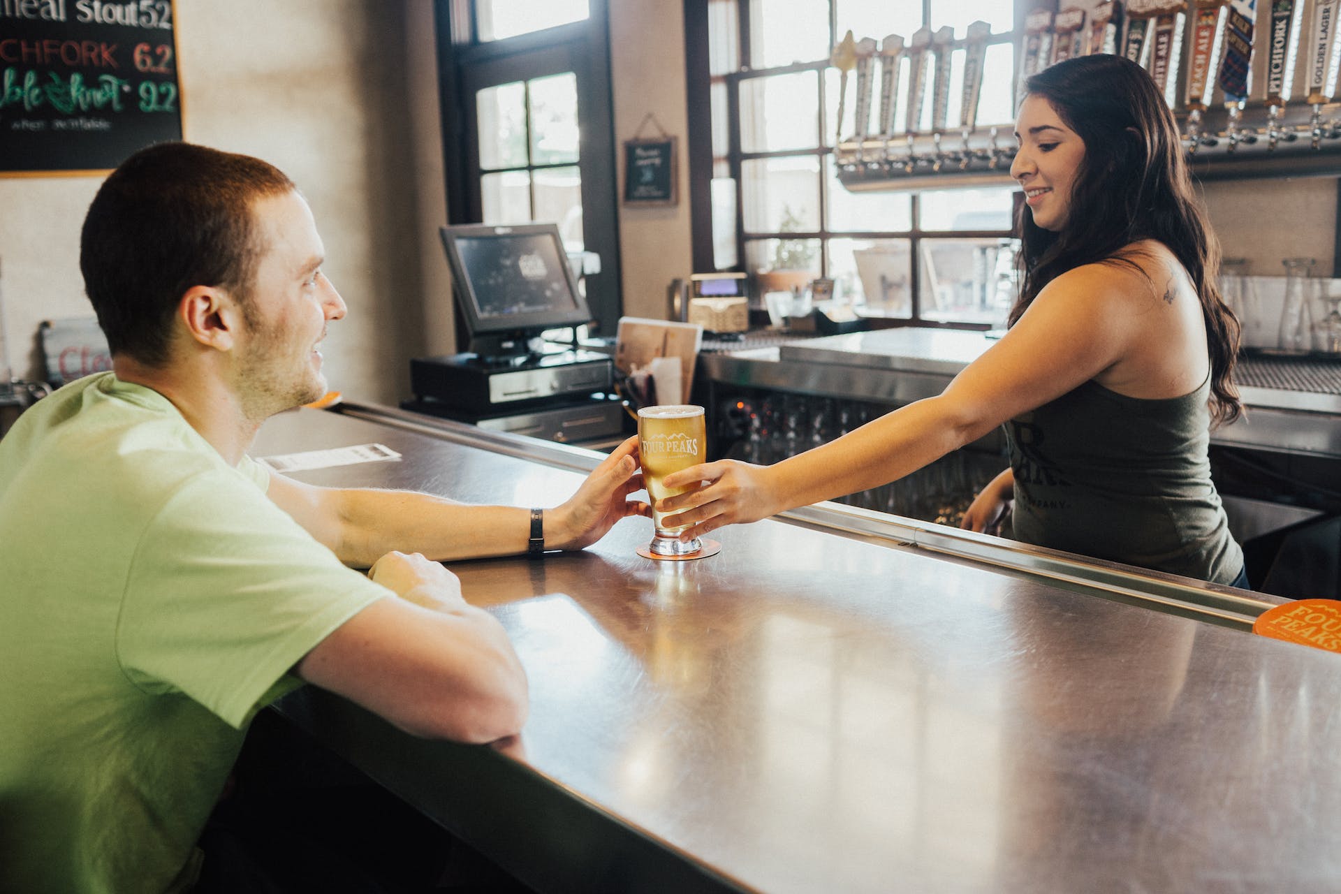A bartender handing a glass of drink to a male customer | Source: Pexels