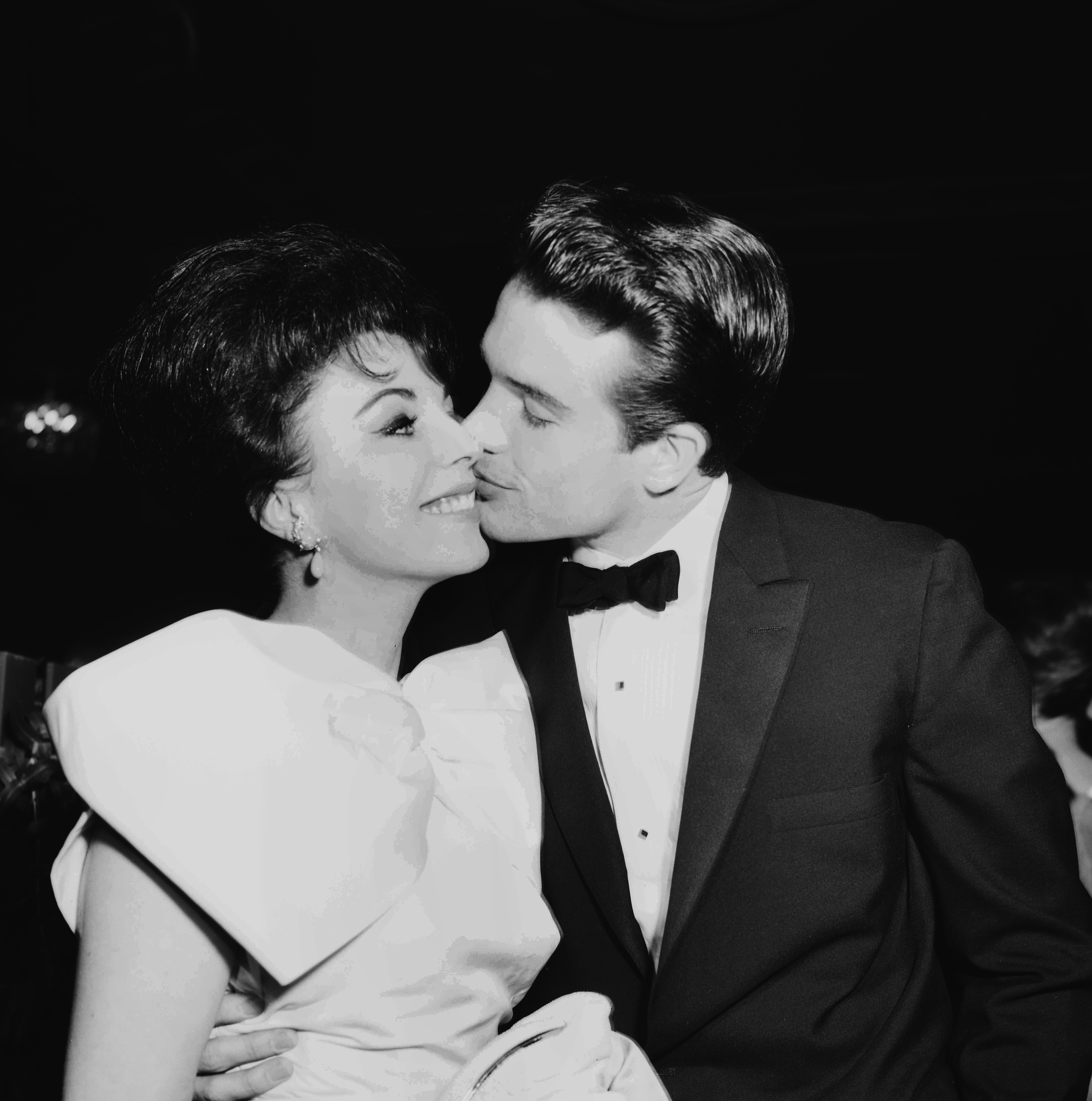 Warren Beatty kisses Joan Collins as they attend a party in Los Angeles, California in 1959. | Source: Getty Images