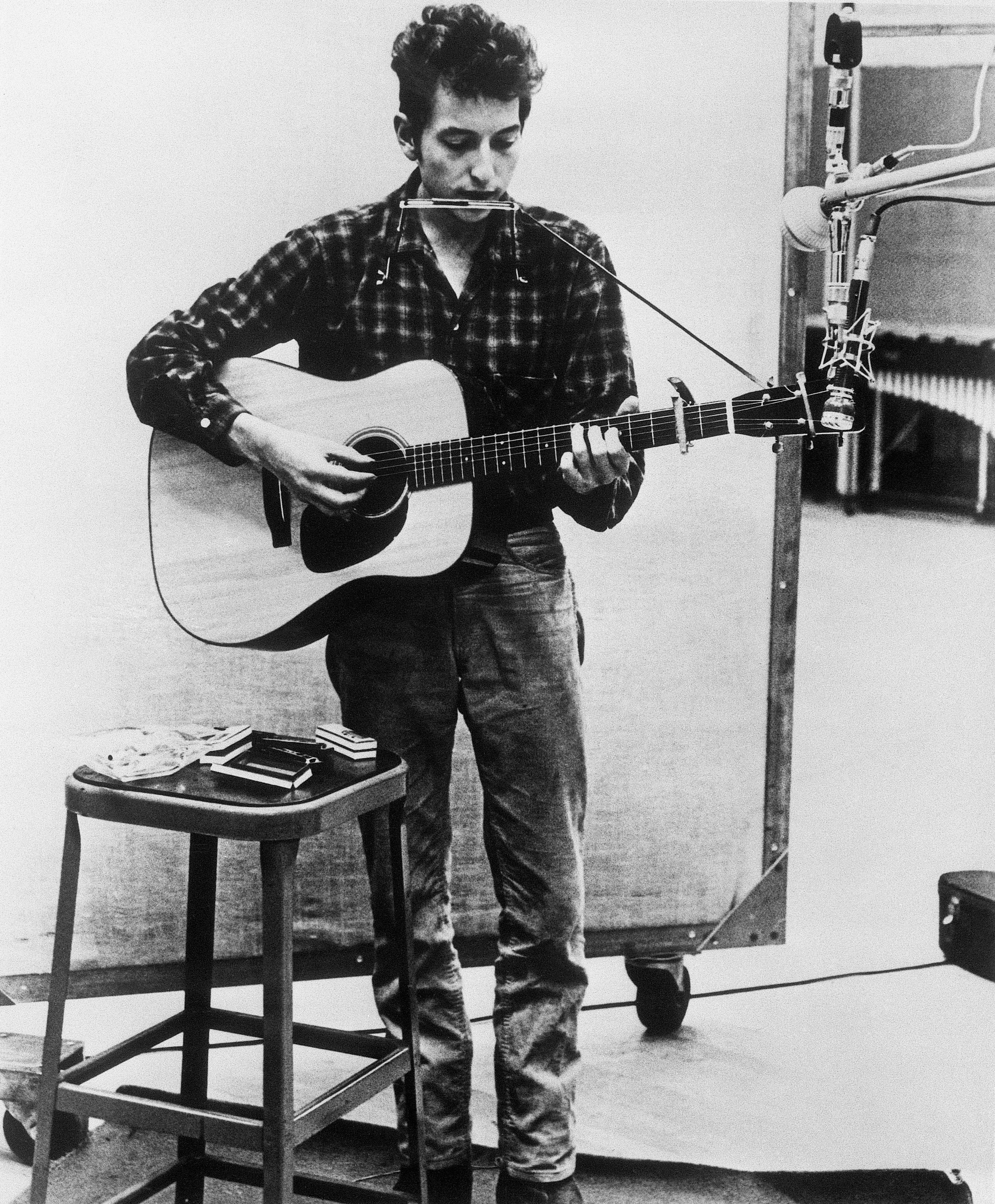 Bob Dylan plays harmonica and guitar in a recording studio in 1962 | Source: Getty Images