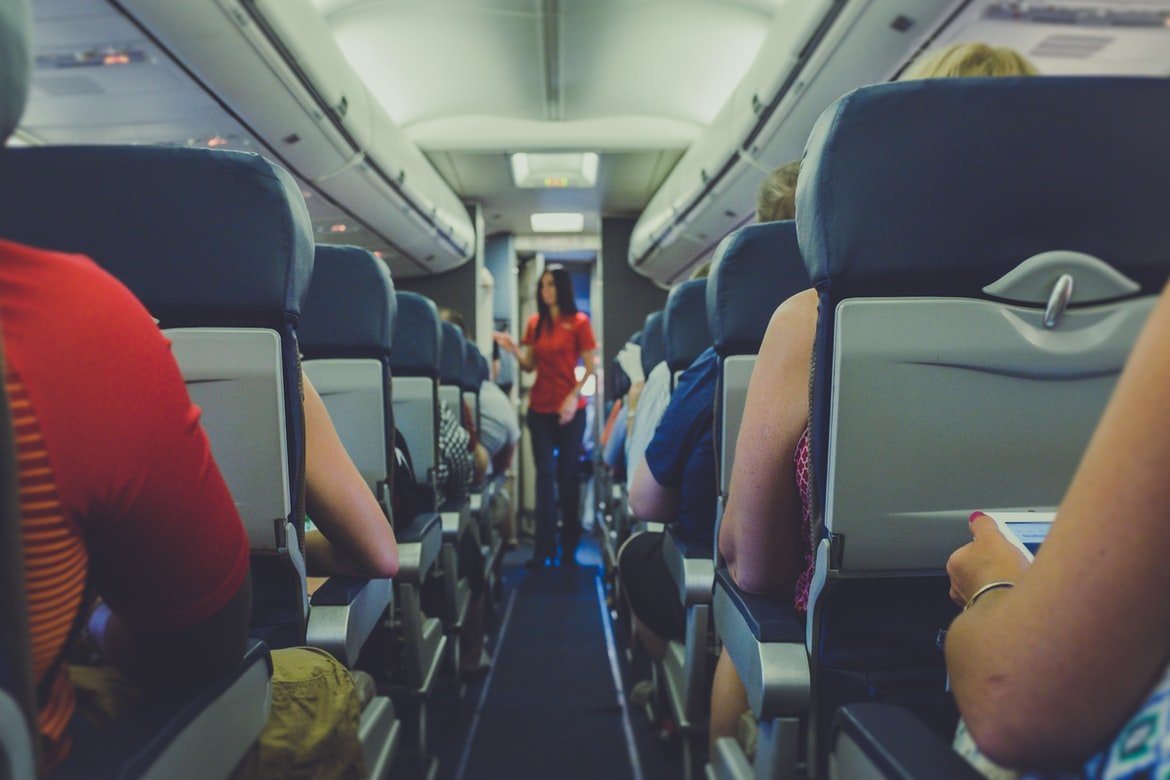 Azafata en pasillo de avión de pasajeros. | Foto: Pexels