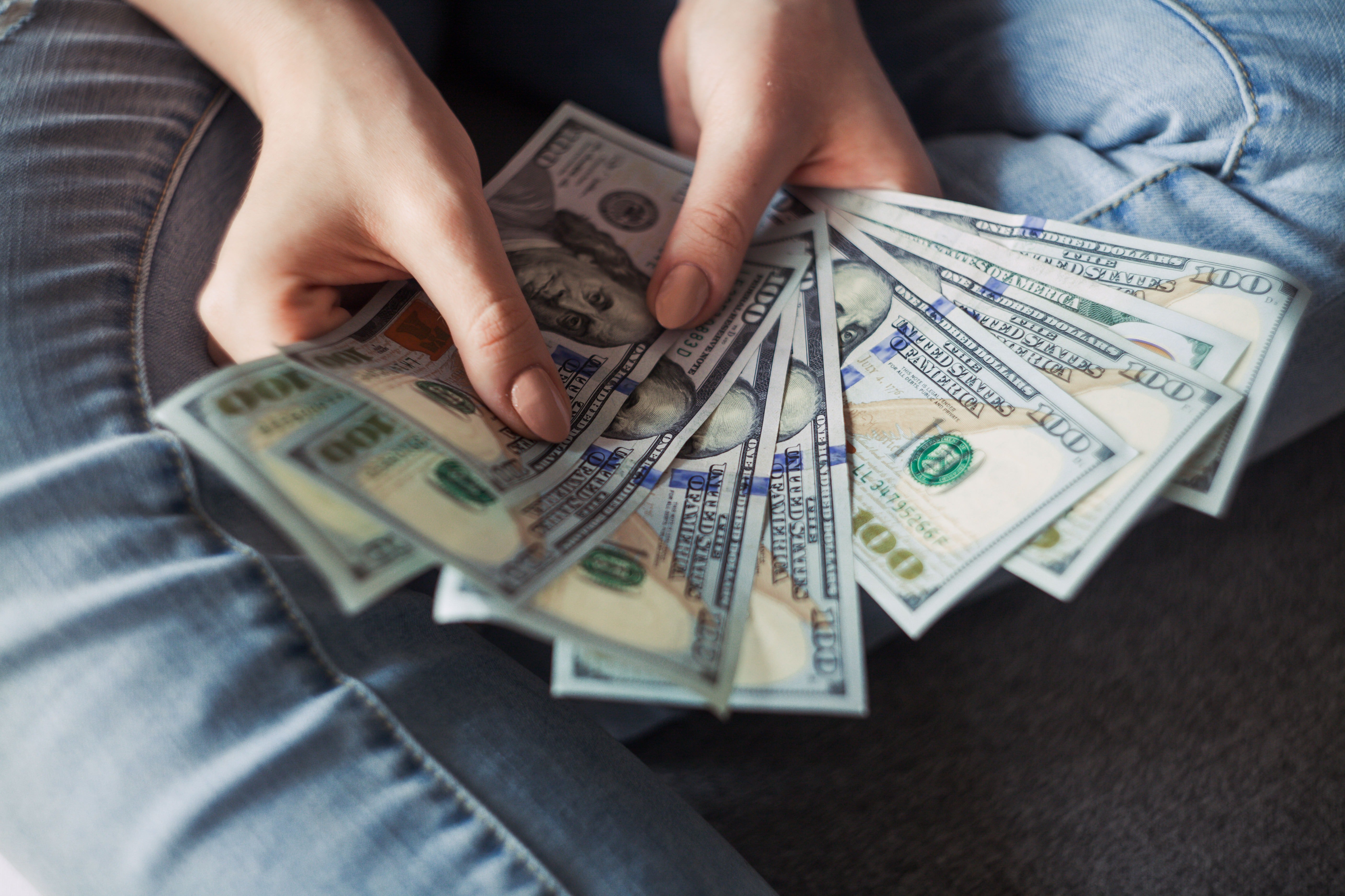 Persona con billetes de 100 dólares en las manos. | Foto: Pexels