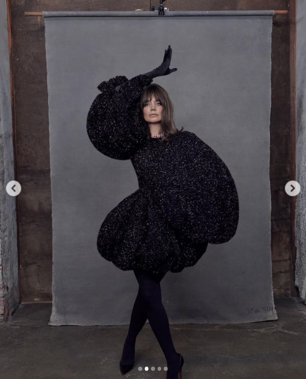 Katie Holmes sports a bedazzled black dress with matching gloves, and heels while posing against a grey background, posted in August 2024 | Source: Instagram/katieholmes