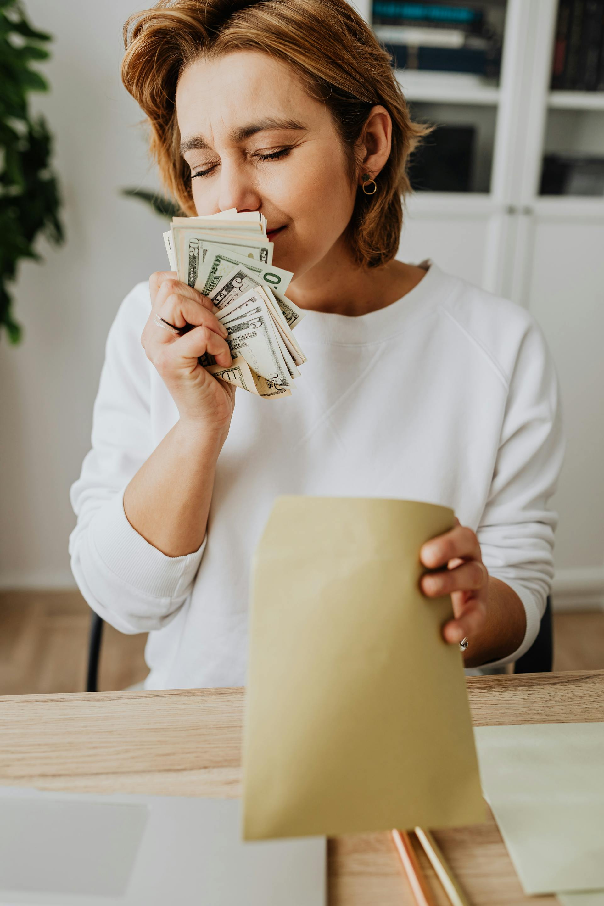 A woman smelling money with her eyes closed | Source: Pexels