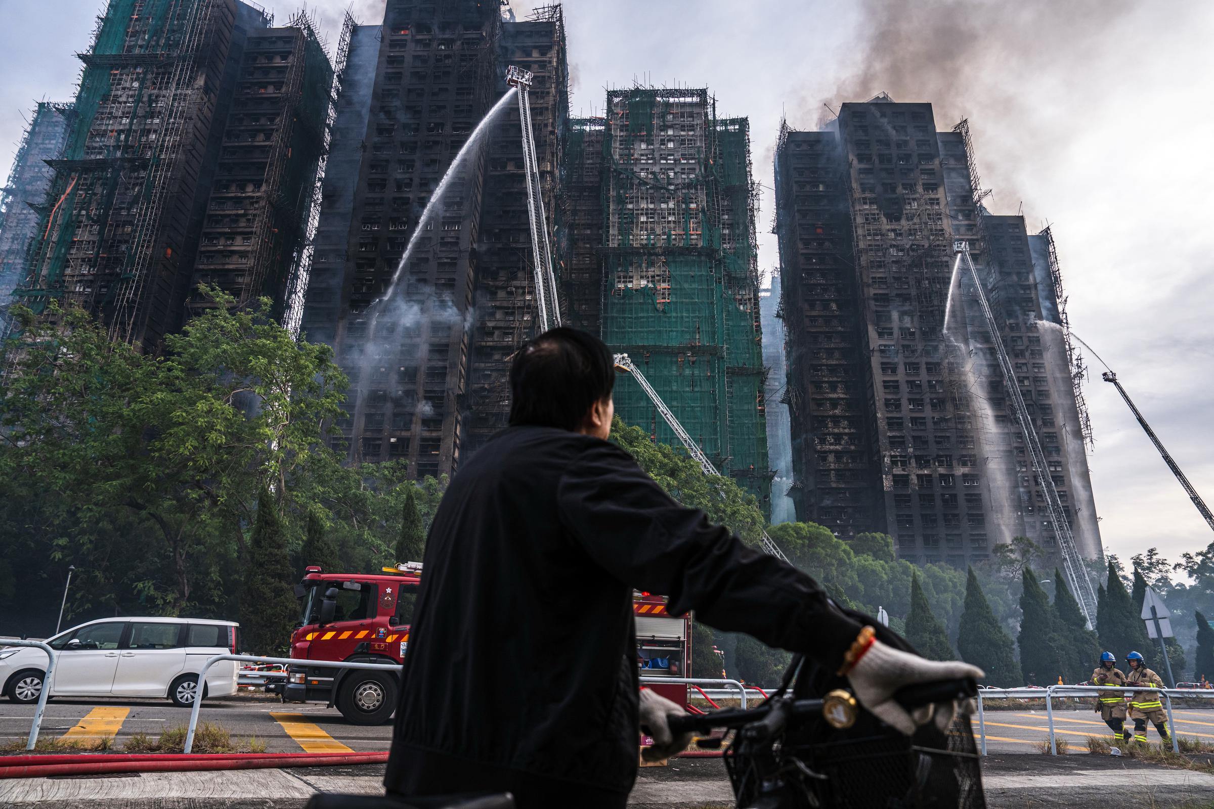 A resident watches as firefighters battle flames at Wang Fuk Court on November 26, 2025 | Source: Getty Images