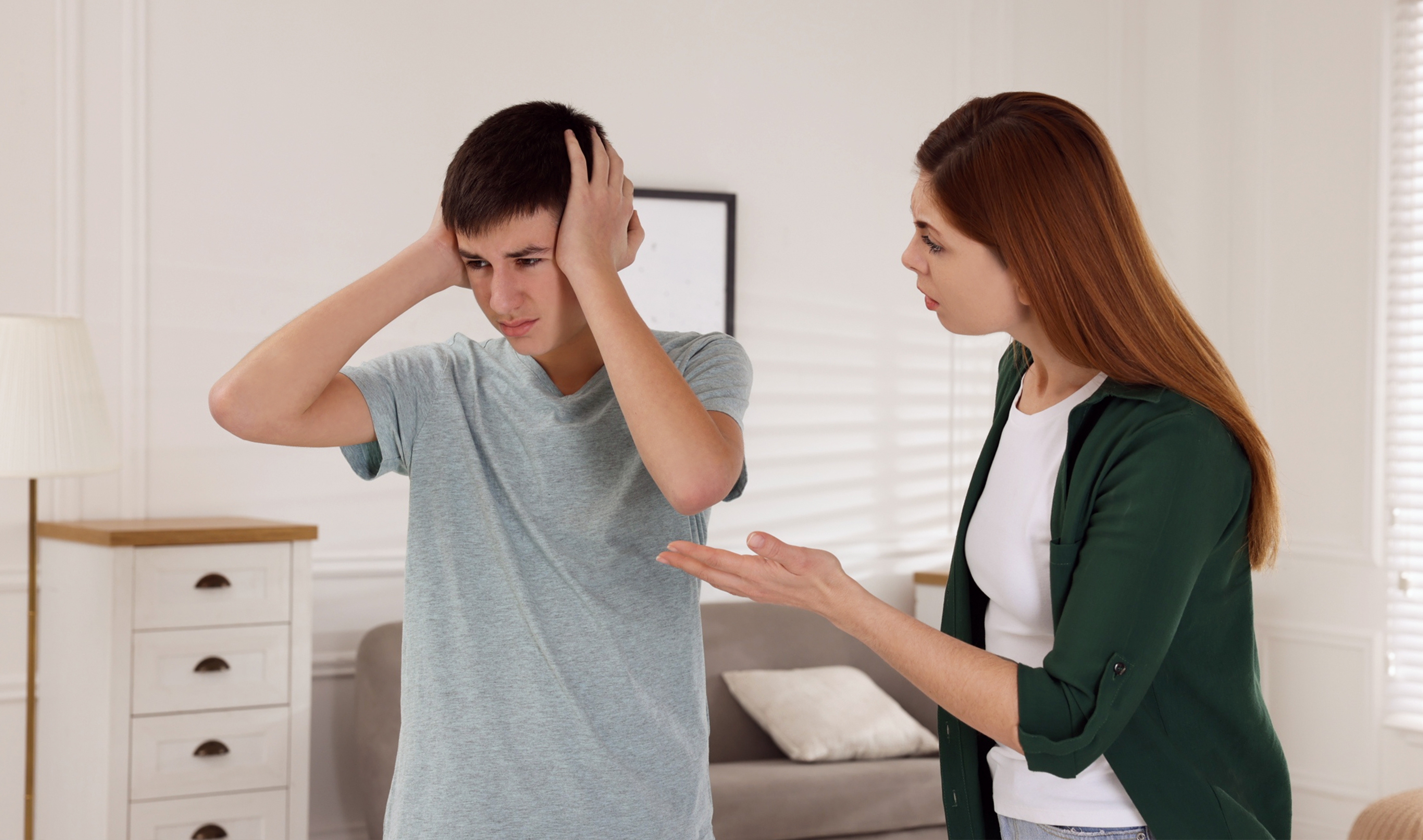 A woman scolding her son as he covers his ears | Source: Shutterstock