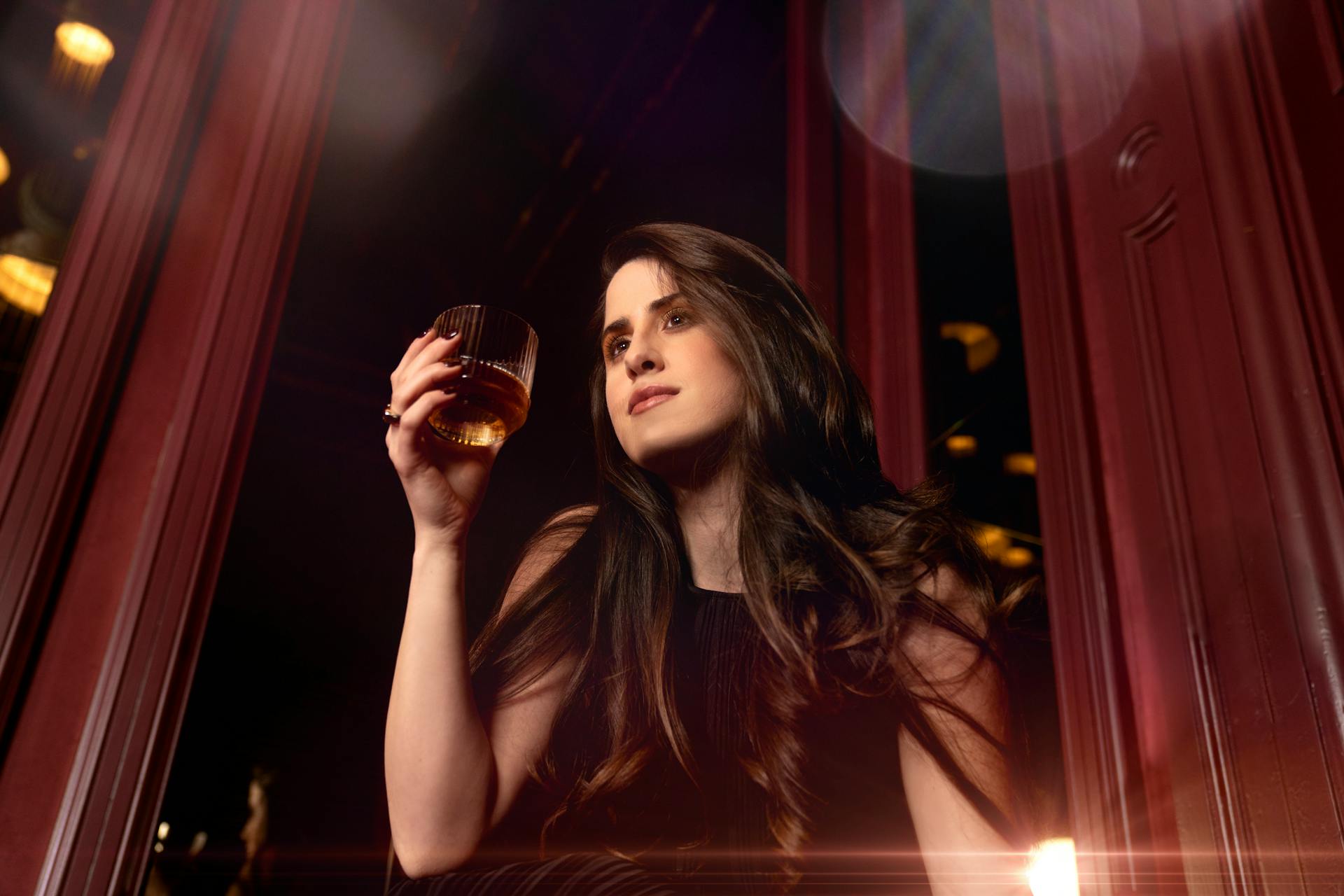 A low-angle shot of a woman holding a glass of whiskey | Source: Pexels