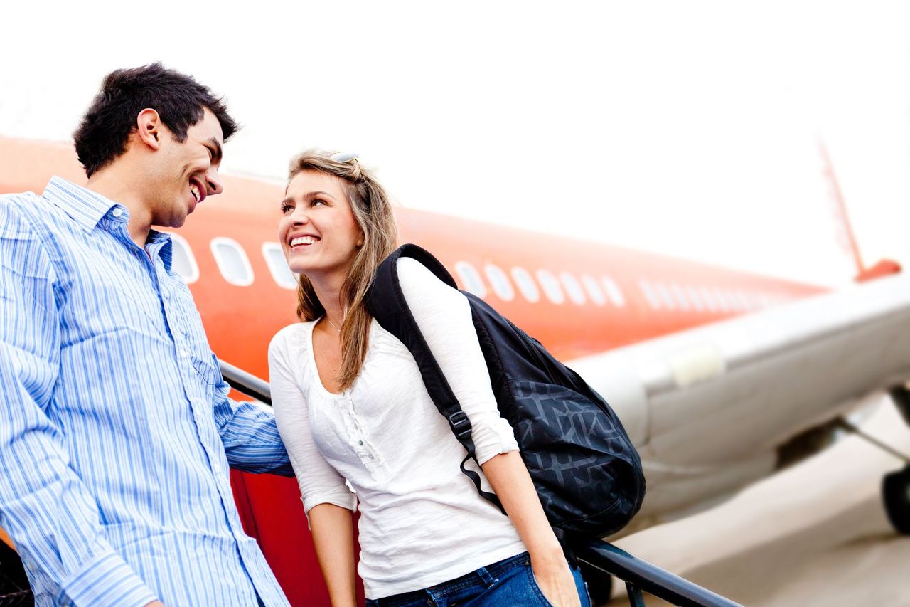 A couple smiling at each other in front of a plane. | Source: Shutterstock