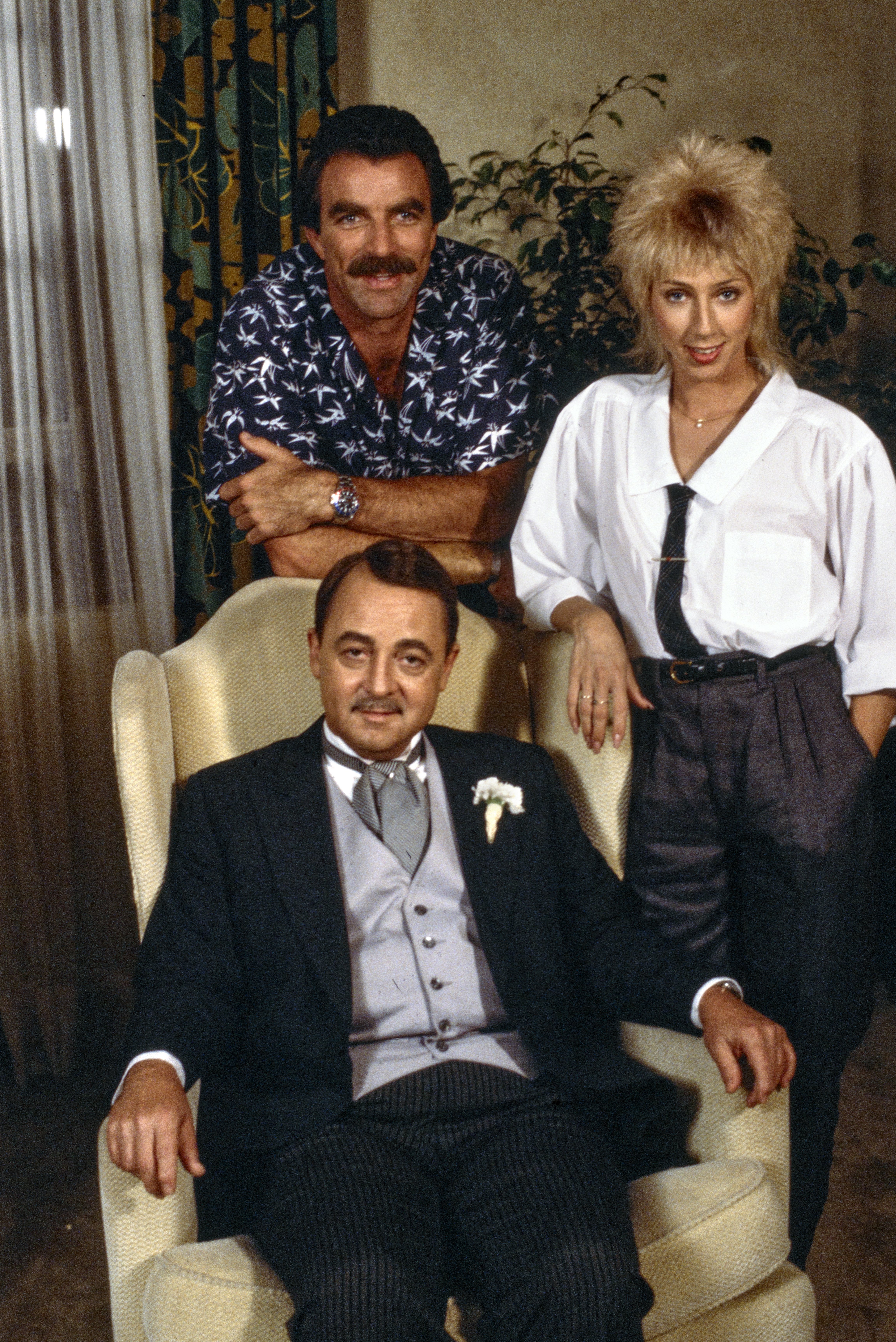Tom Selleck (as Magnum), Jillie Mack (as Sally Ponting), and seated is John Hillerman (as Higgins) in the MAGNUM PI episode, "Professor Jonathan Higgins," which aired January 10, 1985. | Photo: Getty Images
