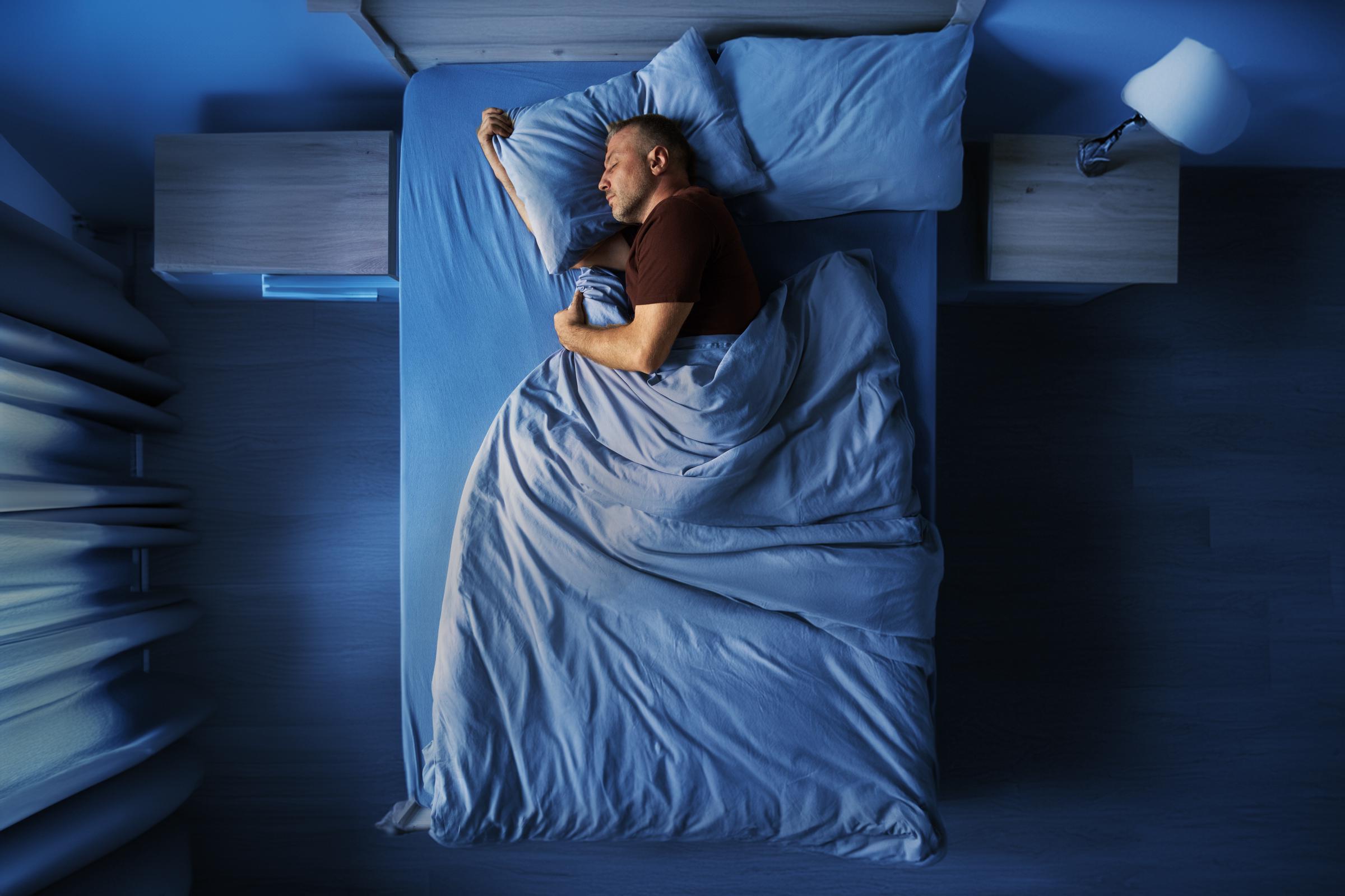 A man sleeping peacefully in a blue bedroom | Source: Shutterstock