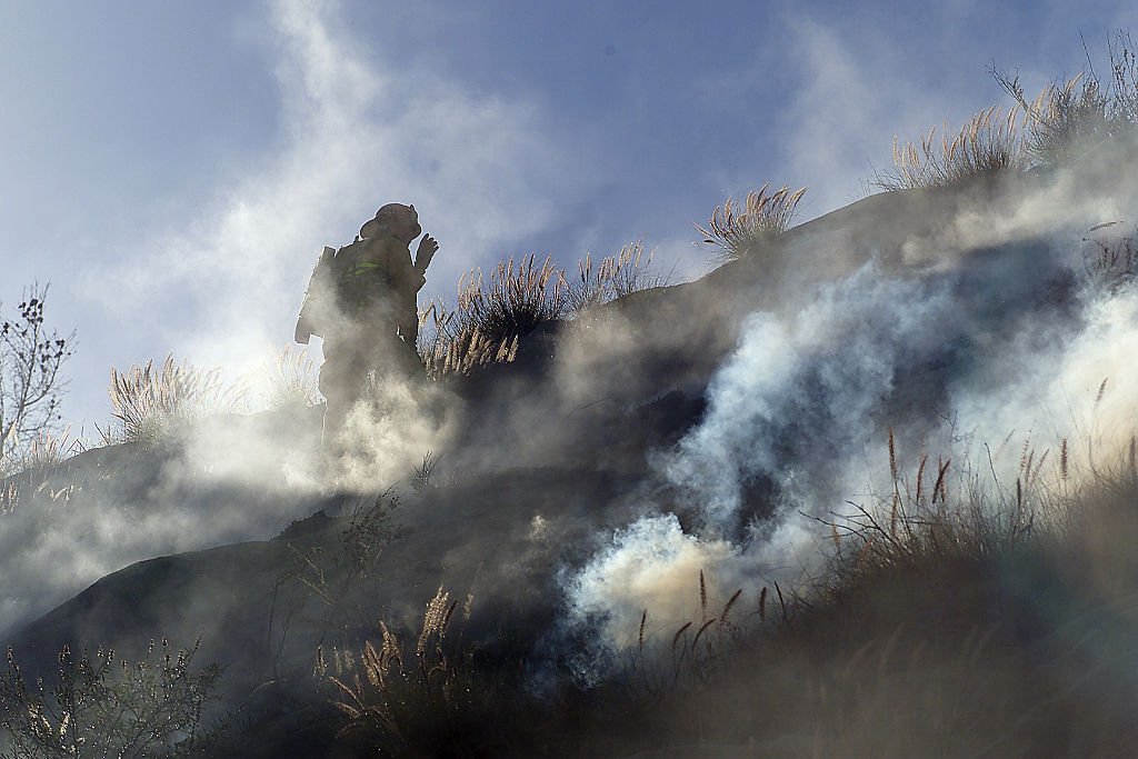 Ein Feuerwehrmann steigt durch Rauch, der durch ein kleines Buschfeuer an der Autobahn 118 östlich des Rocky Peak verursacht wird, einen steilen Hang hinauf (Foto von George Wilhel) Quelle: Getty Images