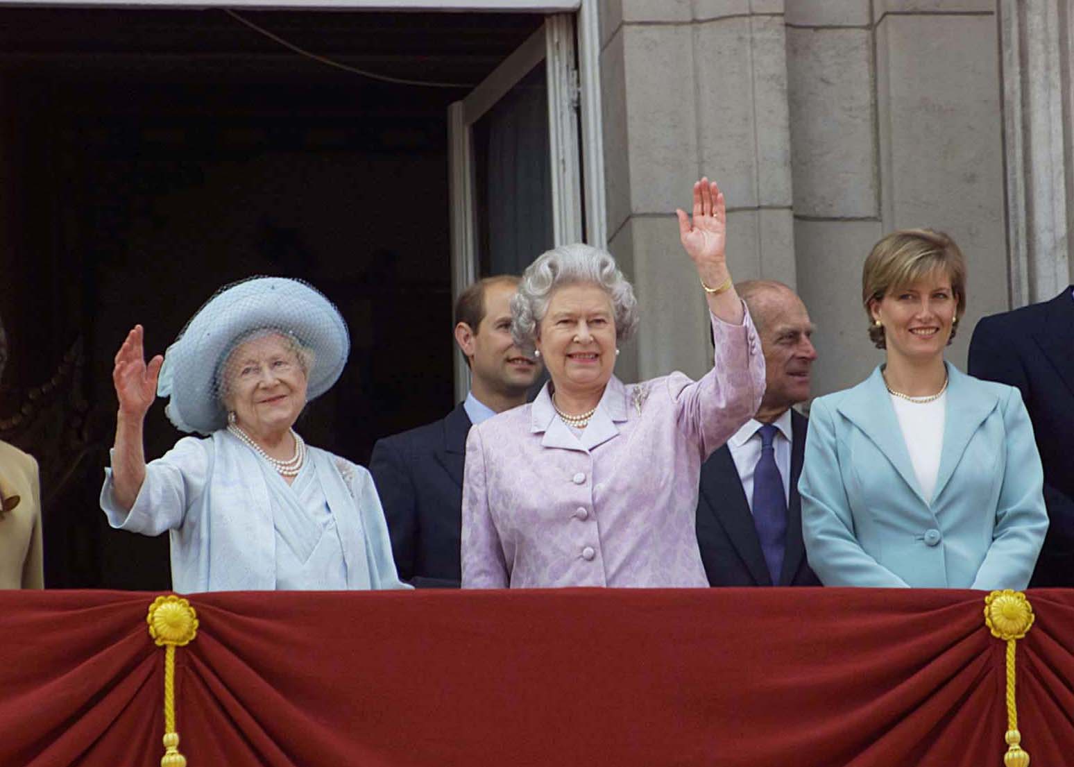 Britain's Queen Mother (L, blue hat & dress) celebrating her 100th birthday with daughter Queen Elizabeth II (C, in lavender), Prince Edward (C, obscured) w. wife Sophie, Countess of Wessex (R) in green & Prince Philip (2R) at Buckingham Palace. August 4, 2000 | Source: Getty Images 
