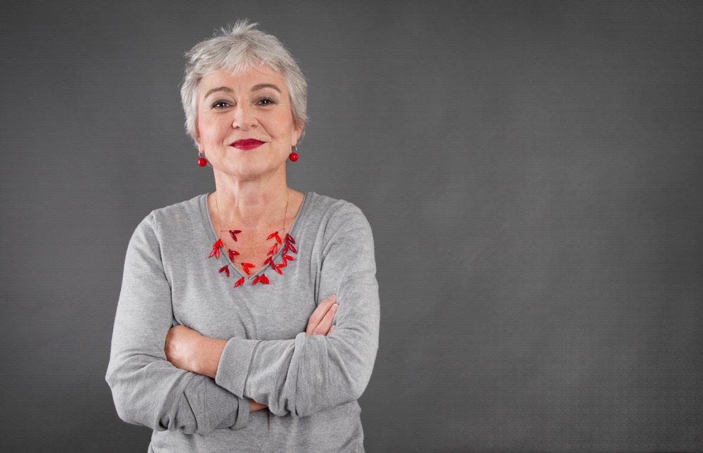 Fröhliche Seniorin mit Armen um den Körper gewickelt. I Quelle: Shutterstock