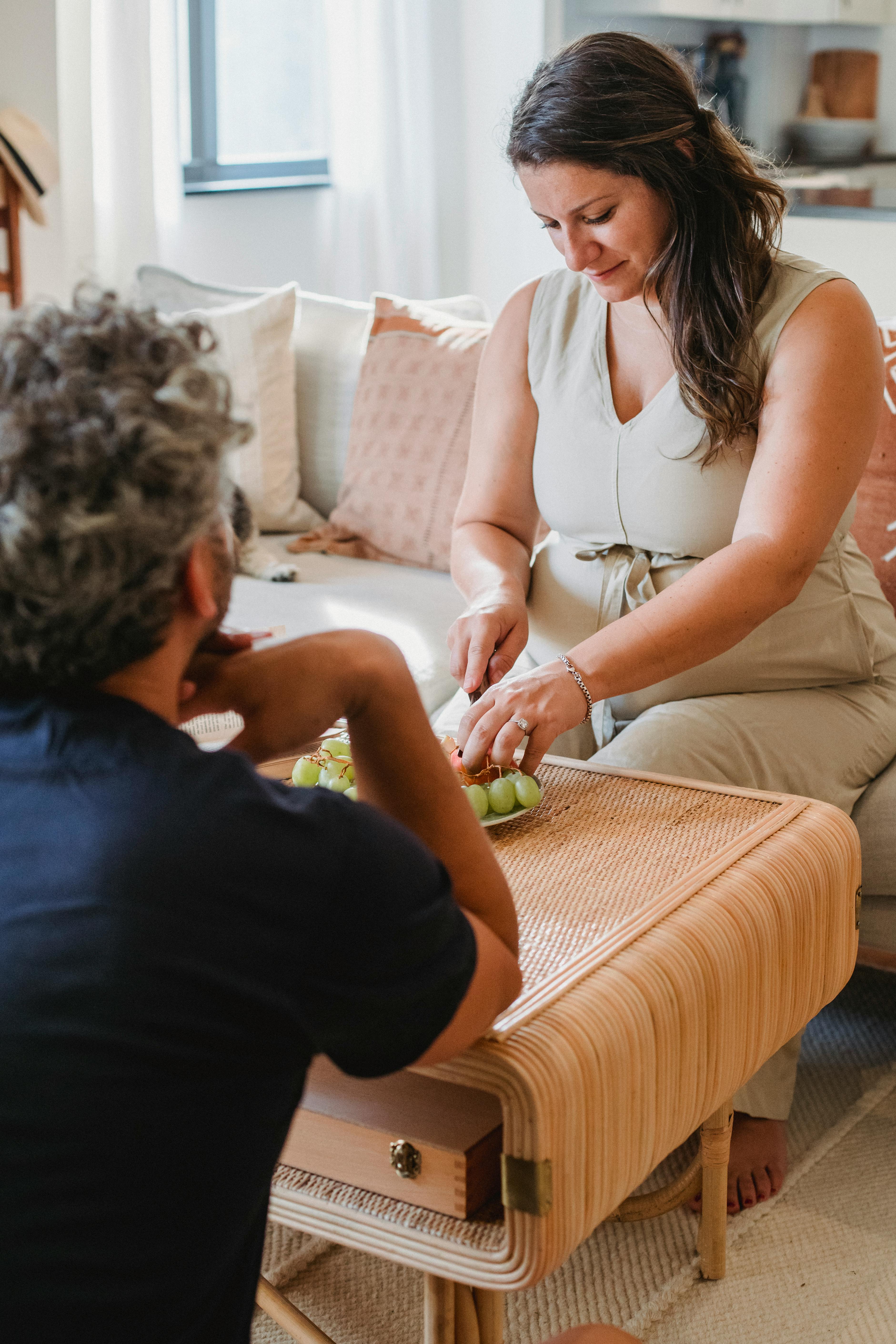 Man and woman sitting in silence as the woman cuts up some grapes | Source: Pexels