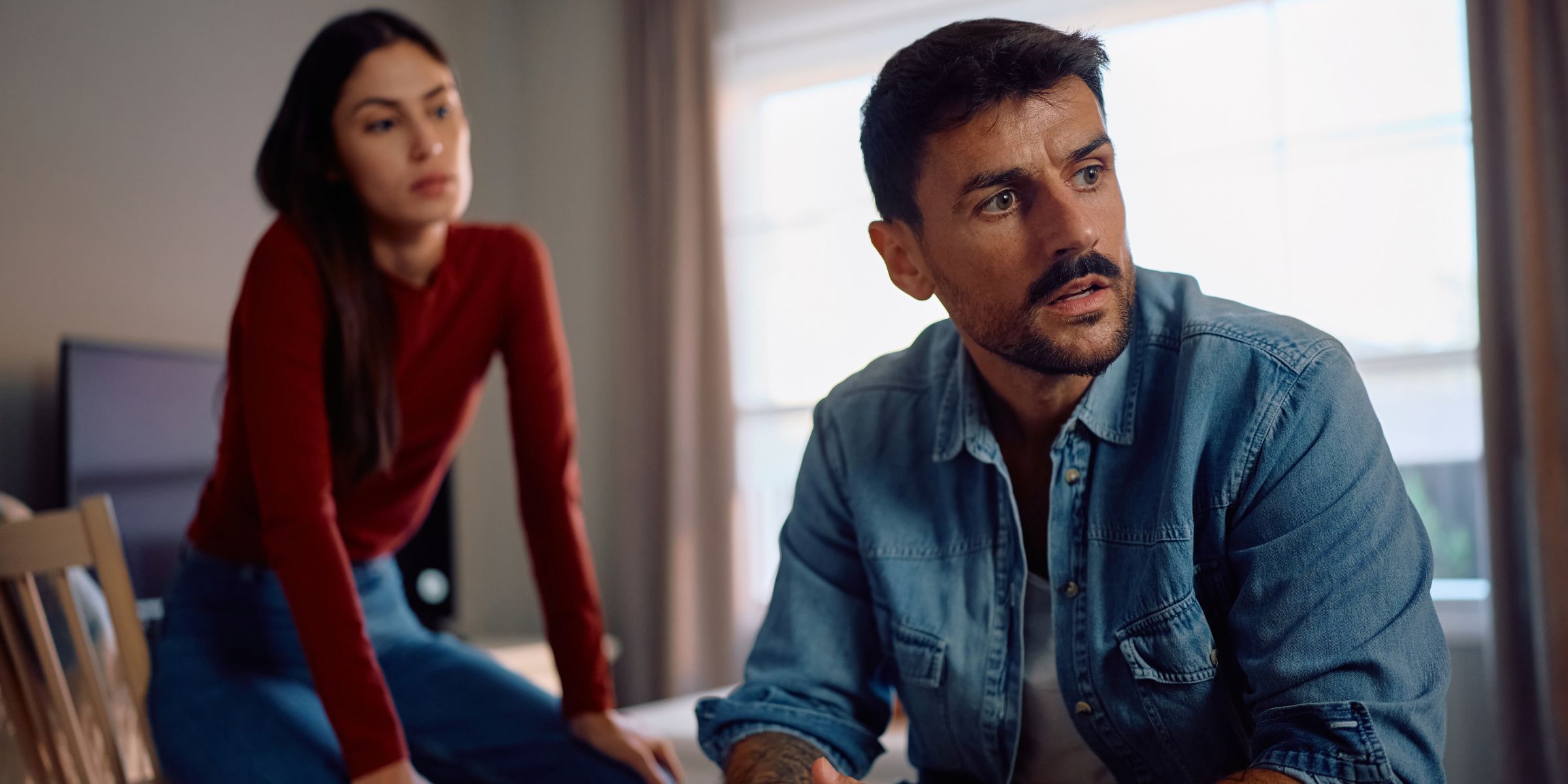 A frustrated man and a woman sitting behind him | Source: Shutterstock