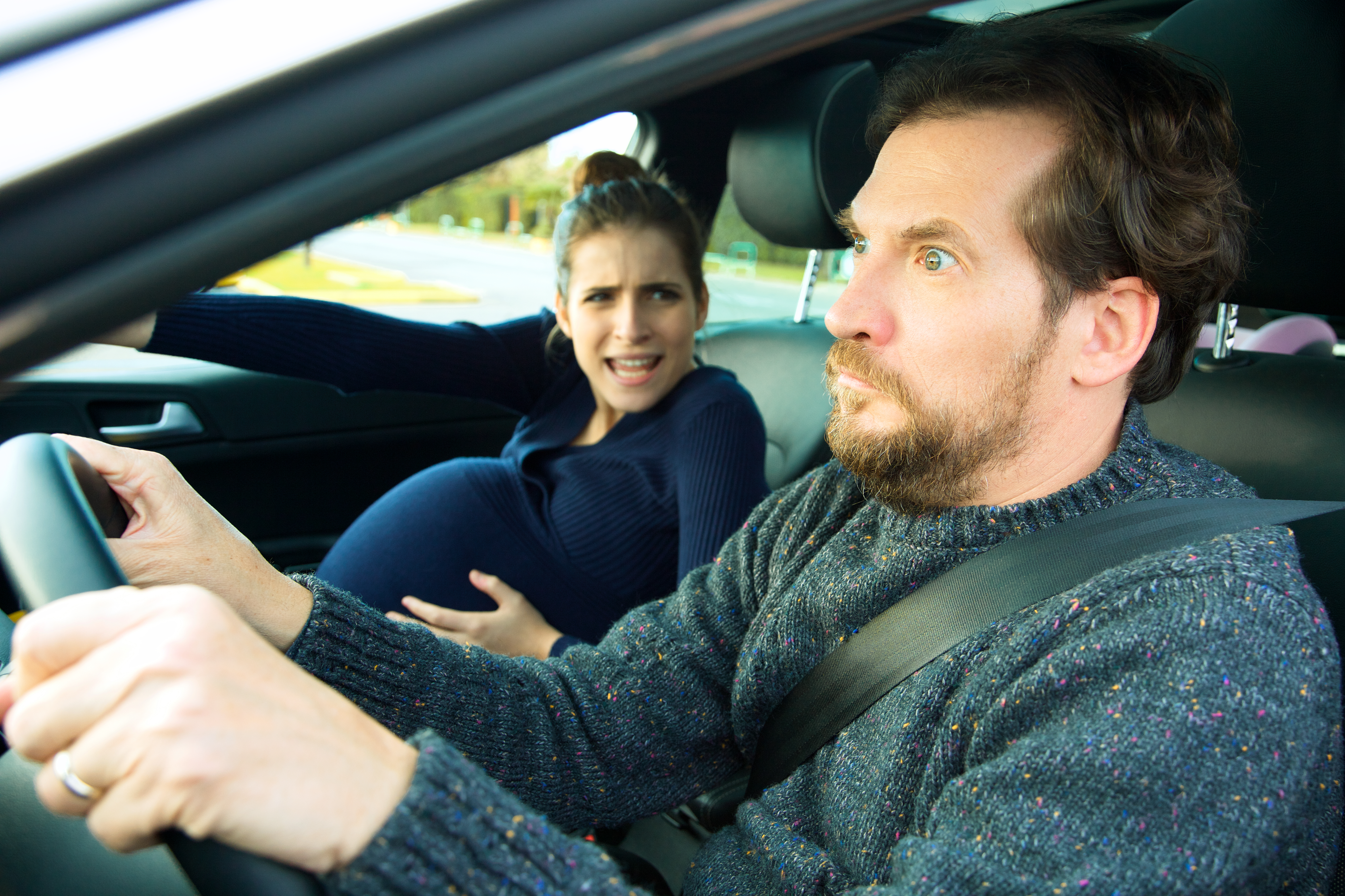 A man looking terrified while driving with a pregnant woman in labor | Source: Shutterstock
