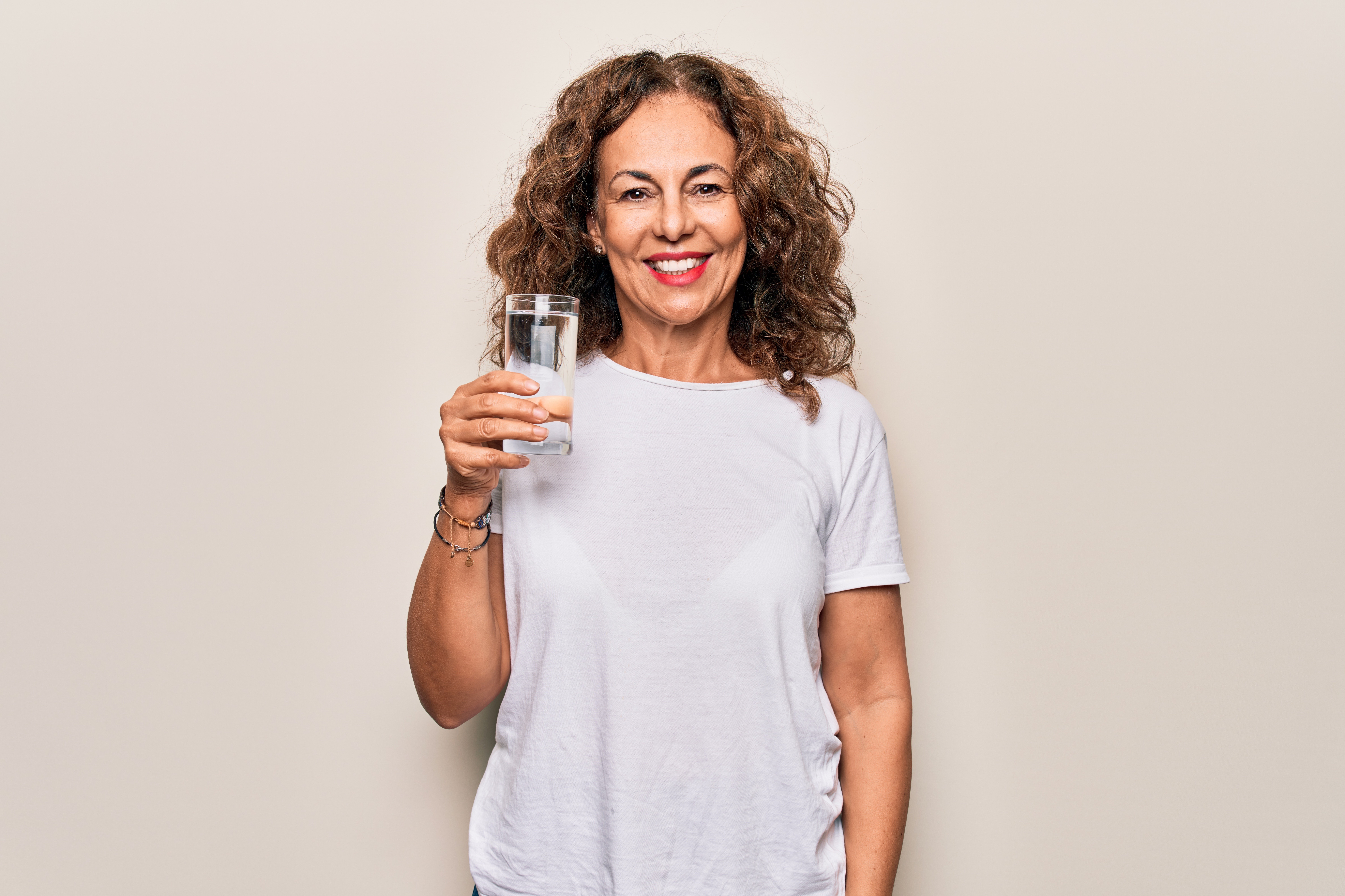 Belle femme d'âge moyen buvant un verre d'eau. | Photo : Shutterstock