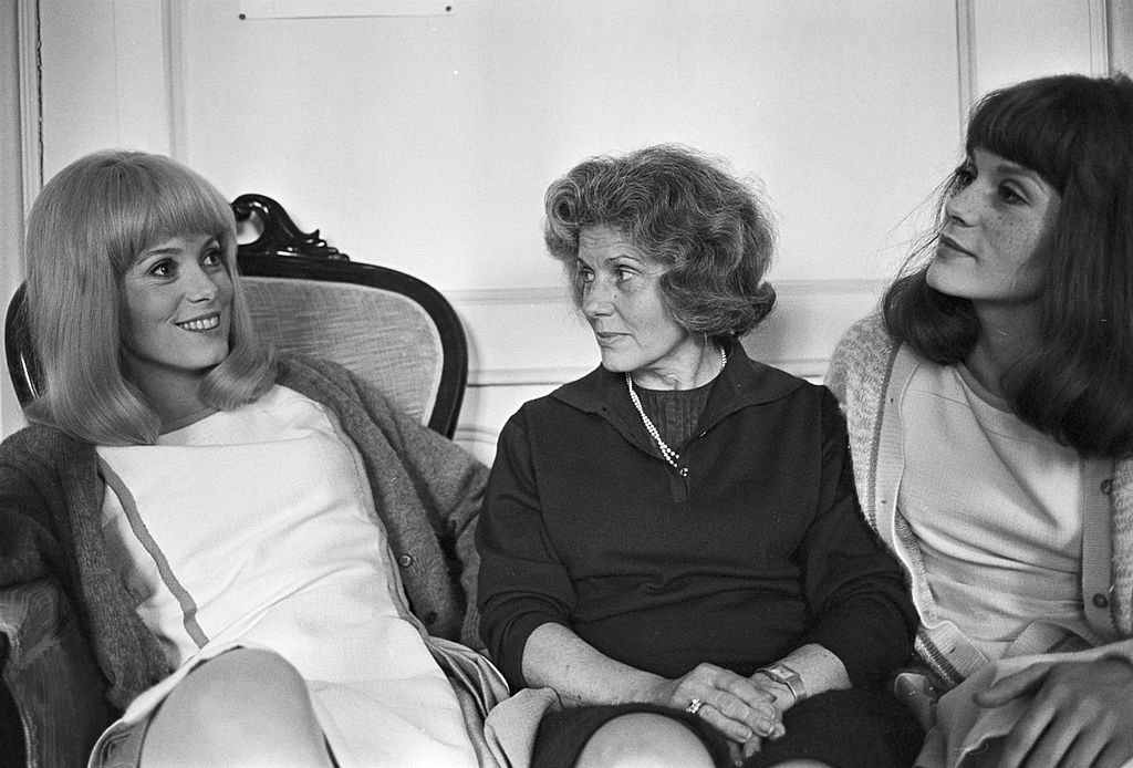 Tournage Du Film 'Les Demoiselles De Rochefort ' De Jacques Demy. Le 13 juin 1966 en France, Catherine DENEUVE, souriante, et sa sœur Françoise DORLEAC entourent leur mère Renée SIMONOT. | Photo : Getty Images