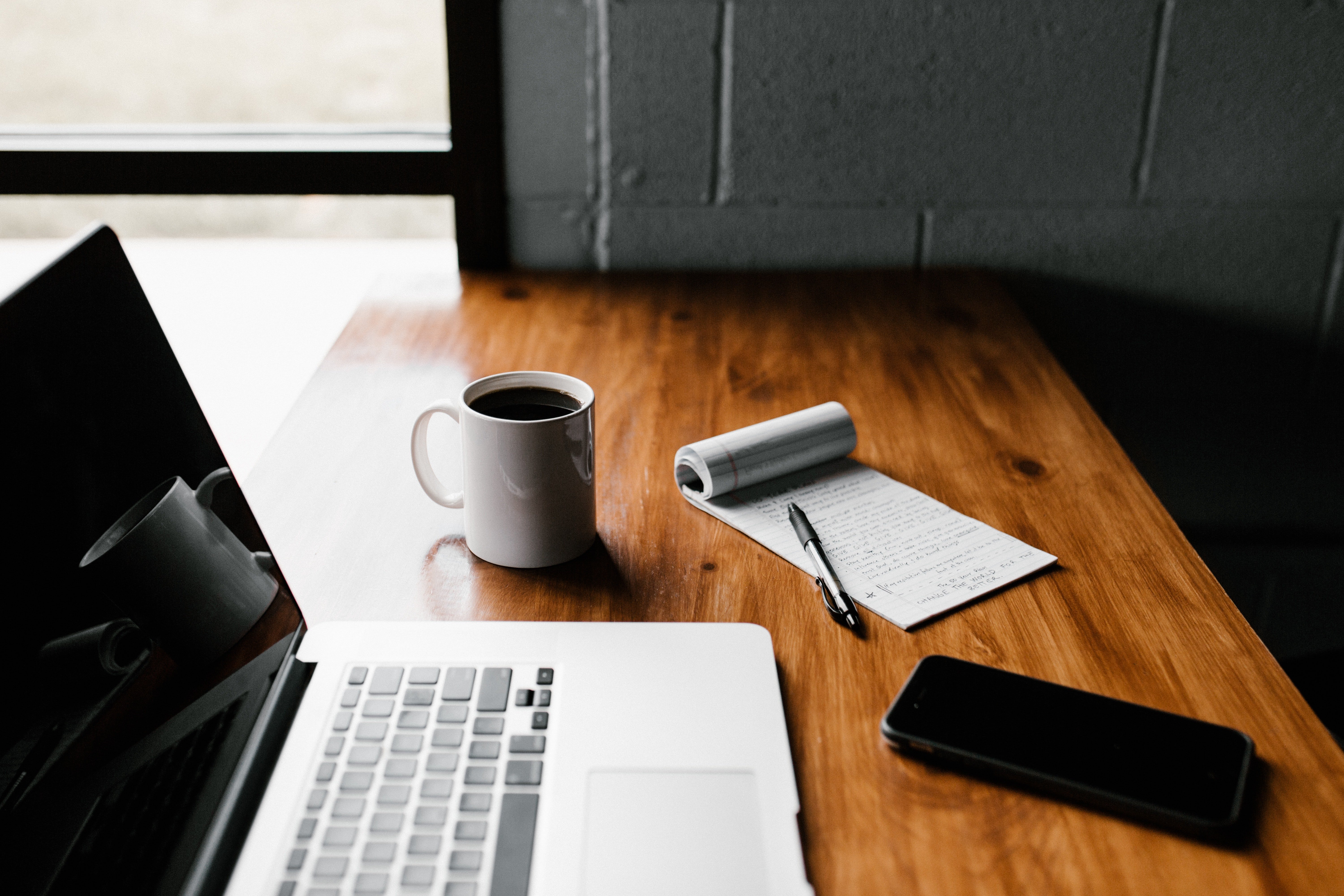 Un macbook et une tache de café sur une table marron. | Photo : Pexels