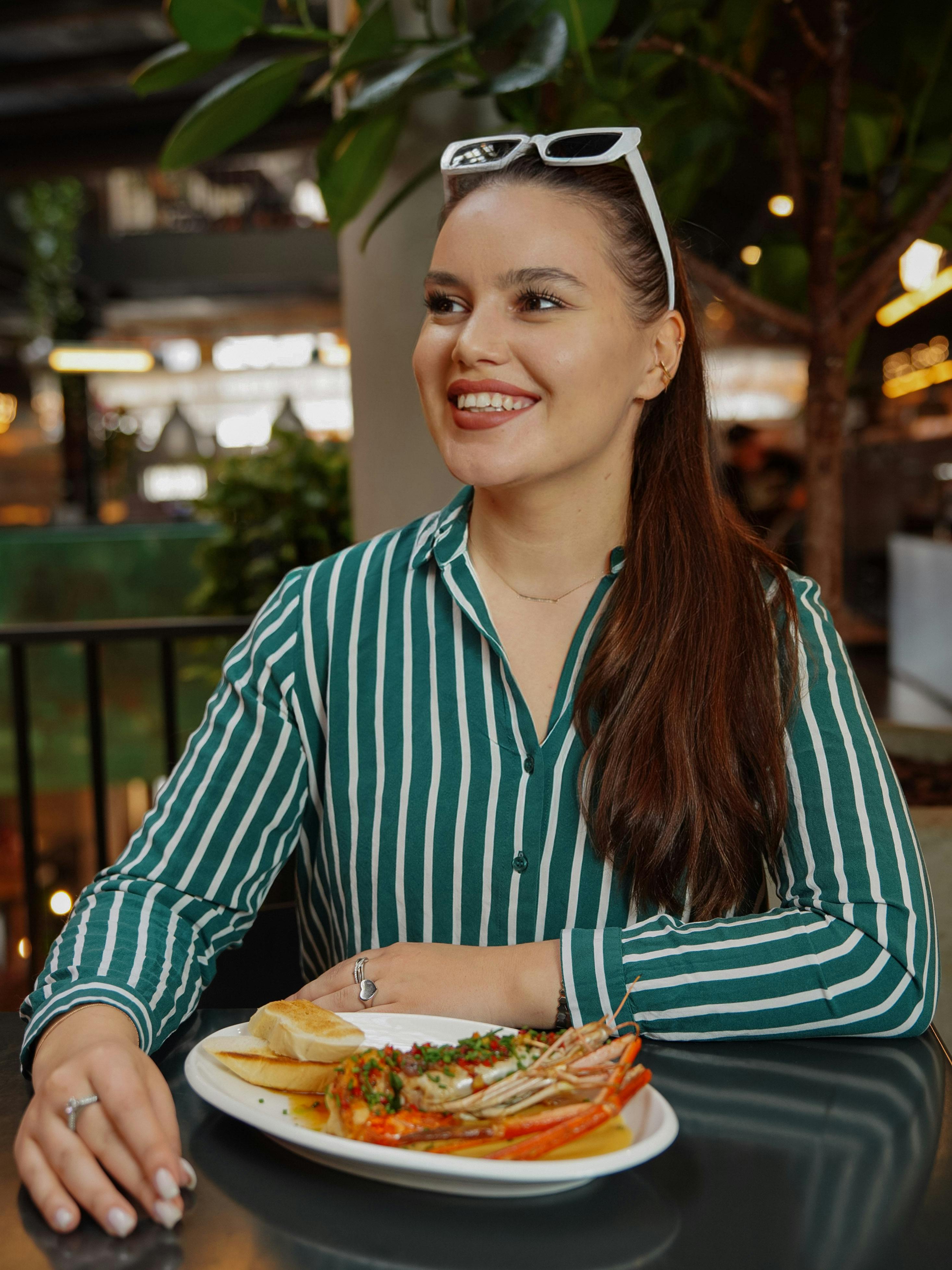 A happy young woman eating a lobster dinner | Source: Pexels