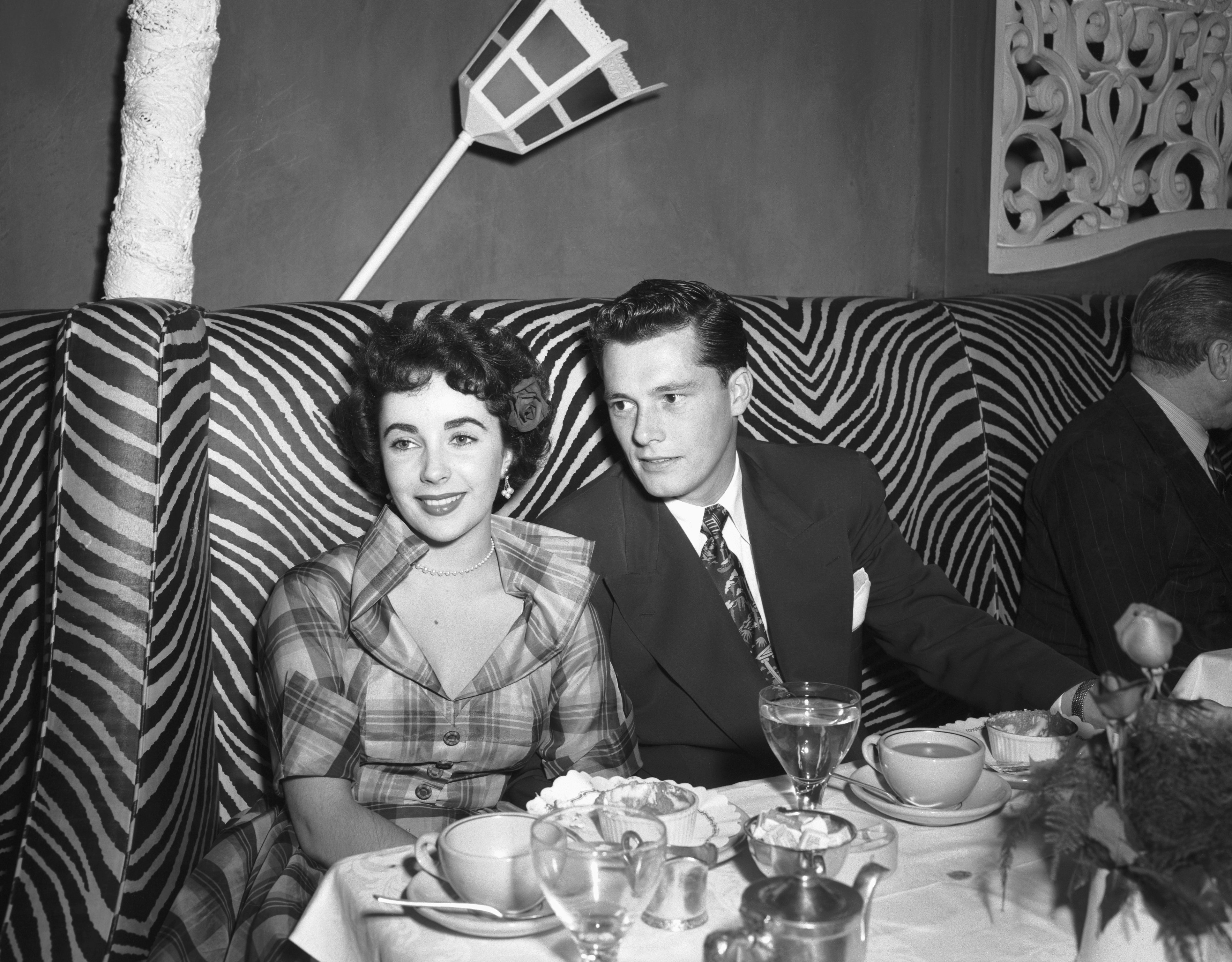 Elizabeth Taylor photographed with Conrad Hilton Jr. in a booth at the El Morocco nightclub. / Source: Getty Images