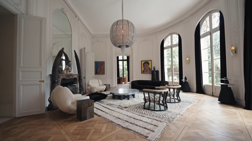 A breathtaking wide shot of the soaring Grand Salon, showcasing its chevron parquet floors, towering arched windows, and a massive spherical crystal chandelier. | Source: YouTube/@Archdigest