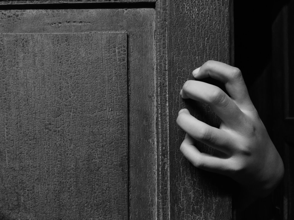 Hand holding an old door. | Photo: Shutterstock