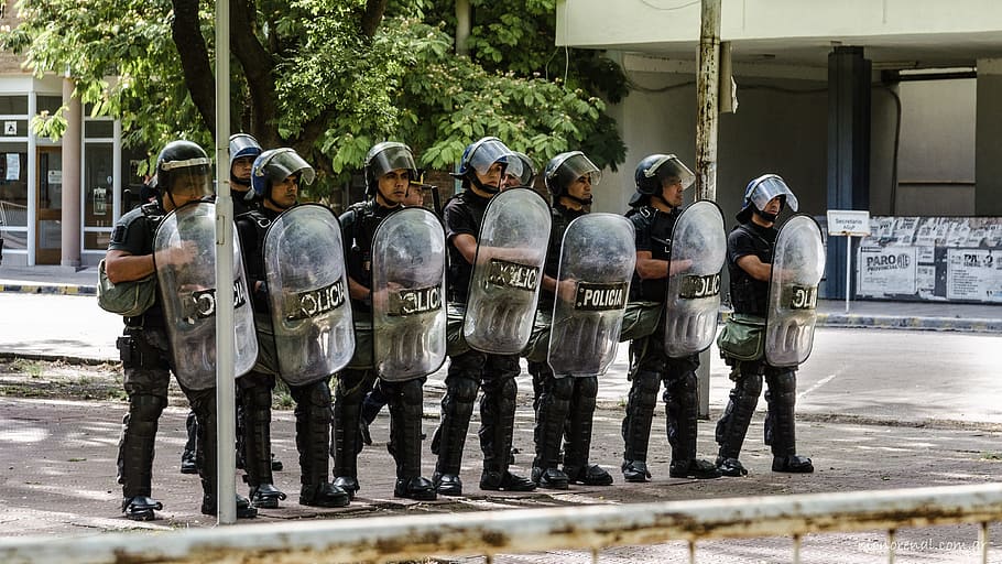 Grupo de oficiales de la policía en formación sosteniendo escudos protectores en una calle. | Foto: PxFuel