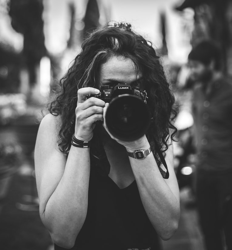 A lady trying to take a photo with a camera | Photo: Unsplash