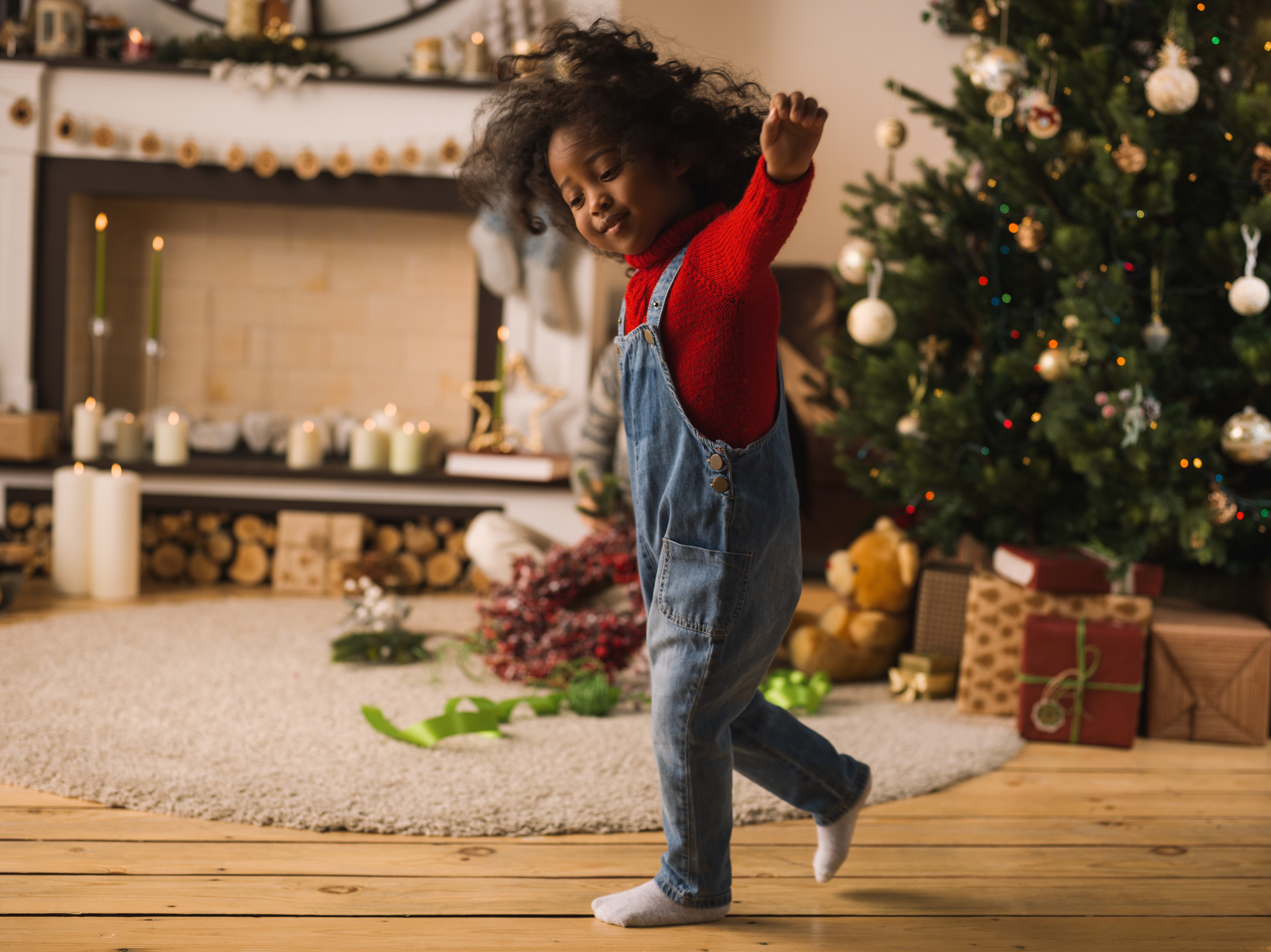 Niña juega feliz frente a árbol de Navidad. | Foto: Shutterstock