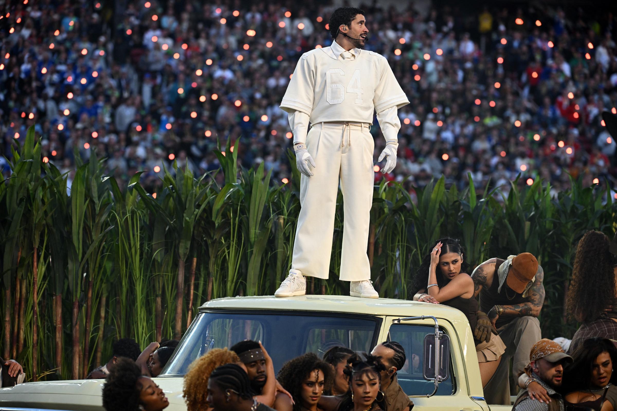 Bad Bunny stands atop a vehicle during his performance while surrounded by dancers, captured in a dynamic moment from the halftime show.